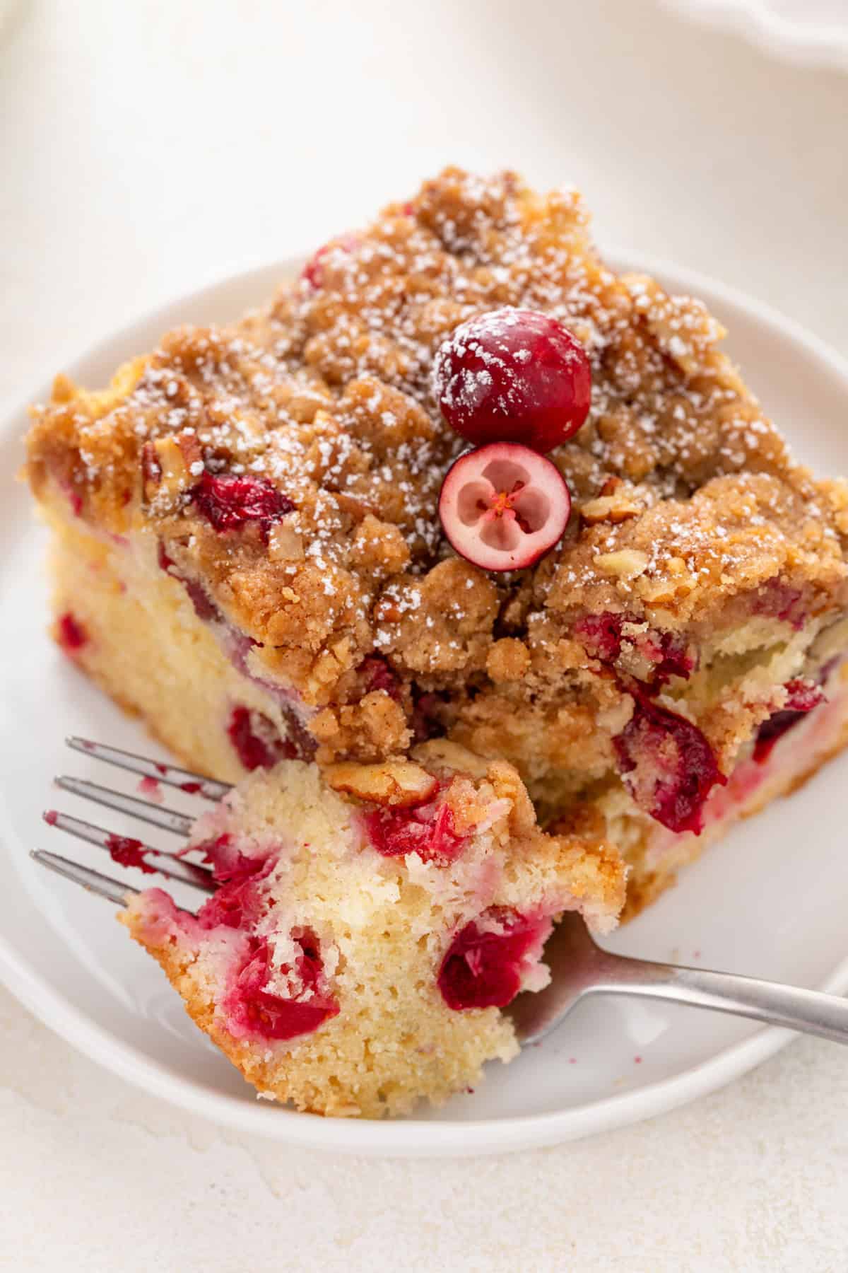 Fork cutting the corner from a slice of cranberry cake.