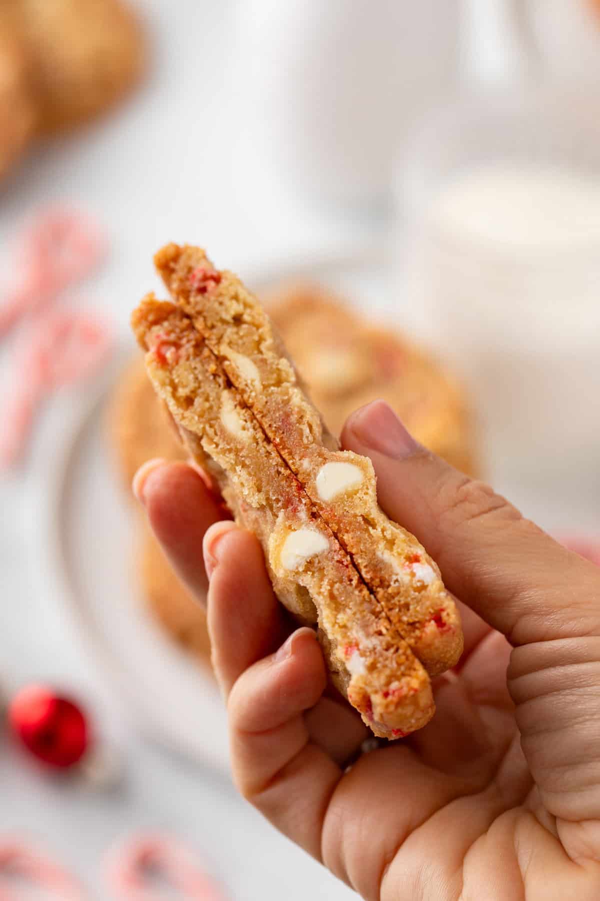 Hand holding a halved white chocolate peppermint cookie.