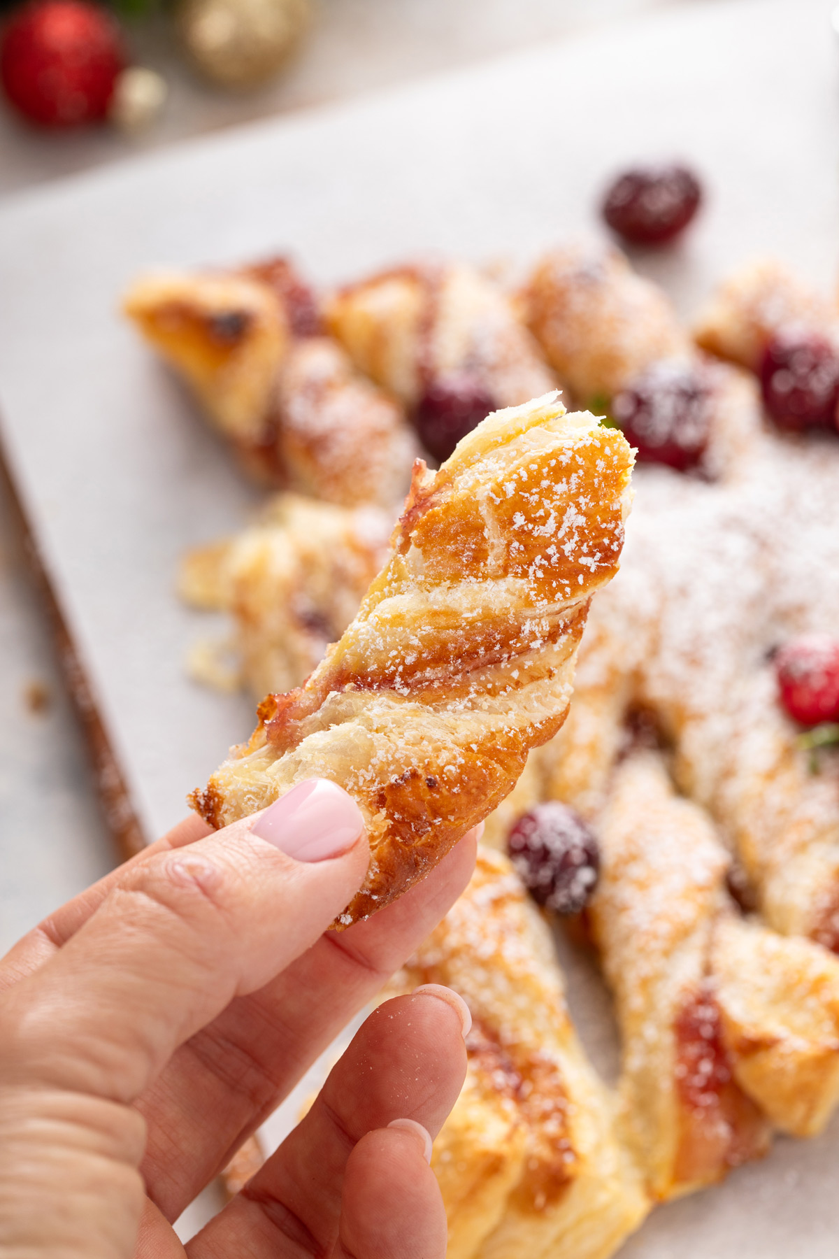 Hand holding up a bite of a sweet puff pastry christmas tree.