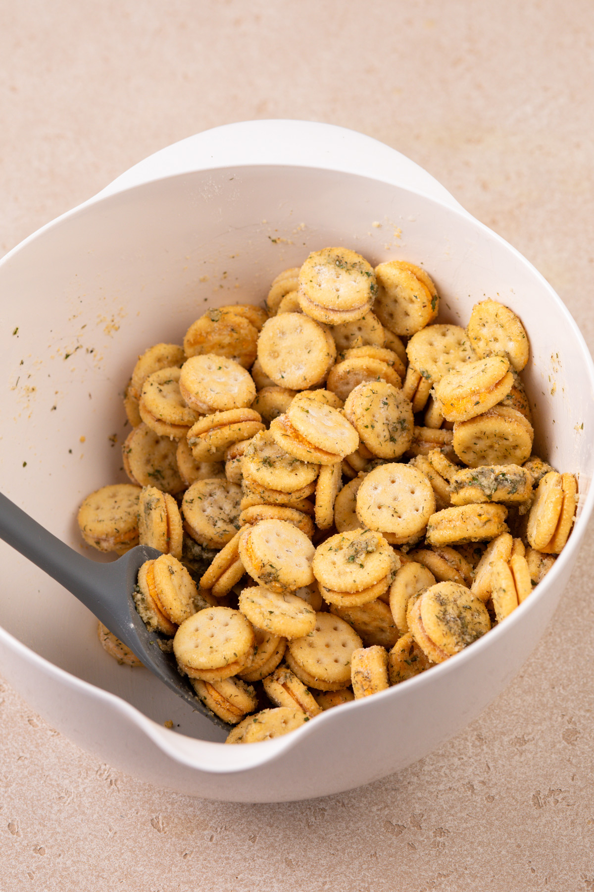 Ranch crackers being stirred together in a white bowl.