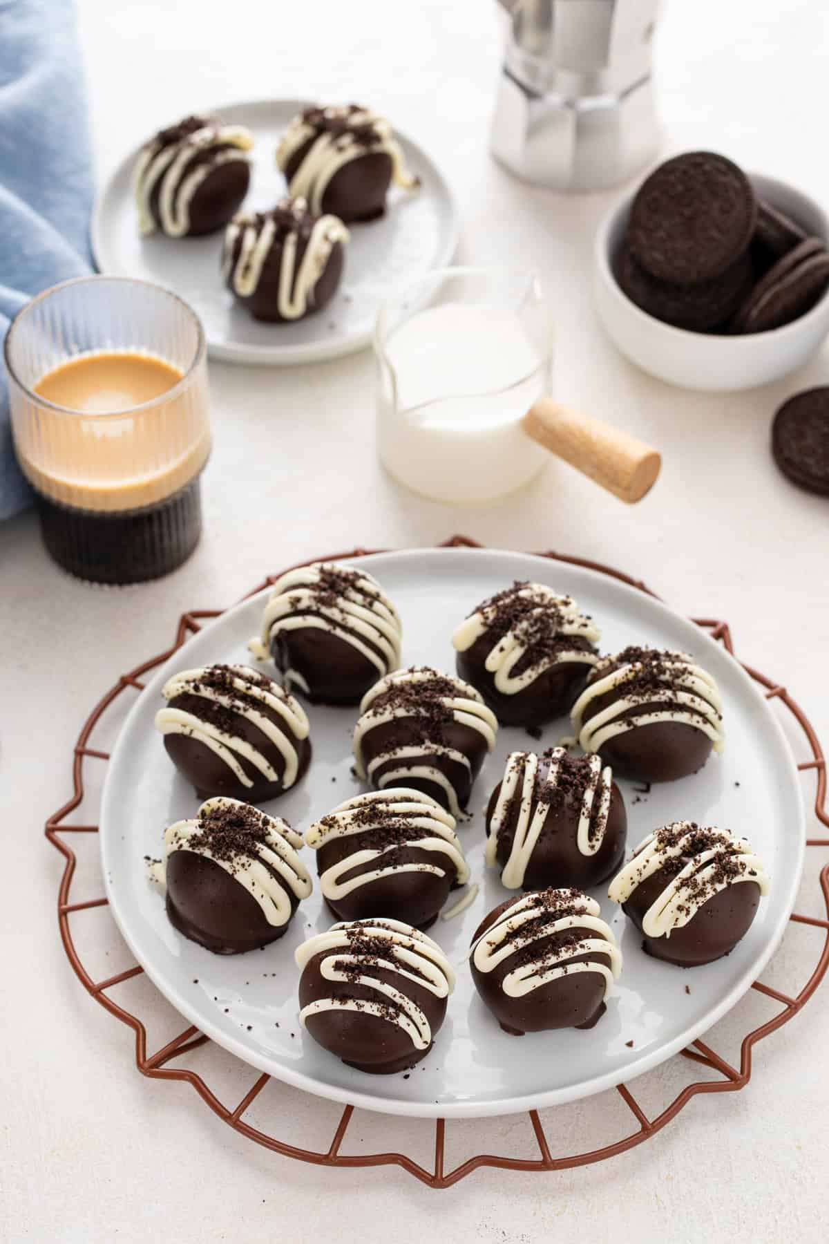 White plate filled with oreo truffles set next to a cup of coffee.