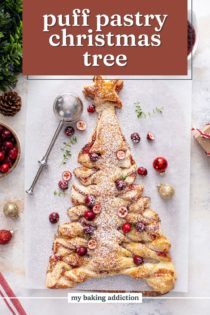 Overhead view of a puff pastry christmas tree filled with cranberry sauce and topped with powdered sugar and cranberries. Text overlay includes recipe name.