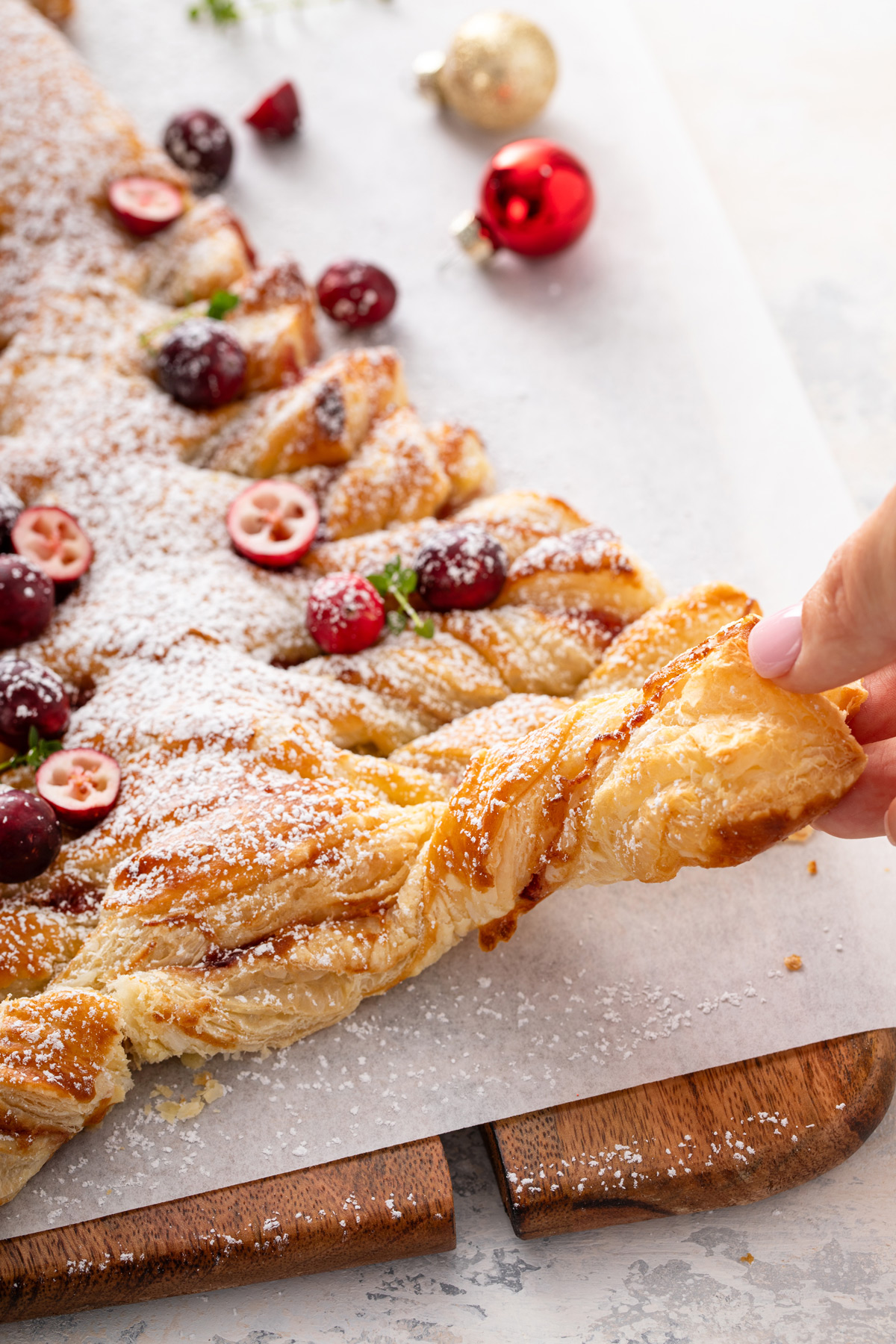 Hand tearing off a branch from a puff pastry christmas tree.