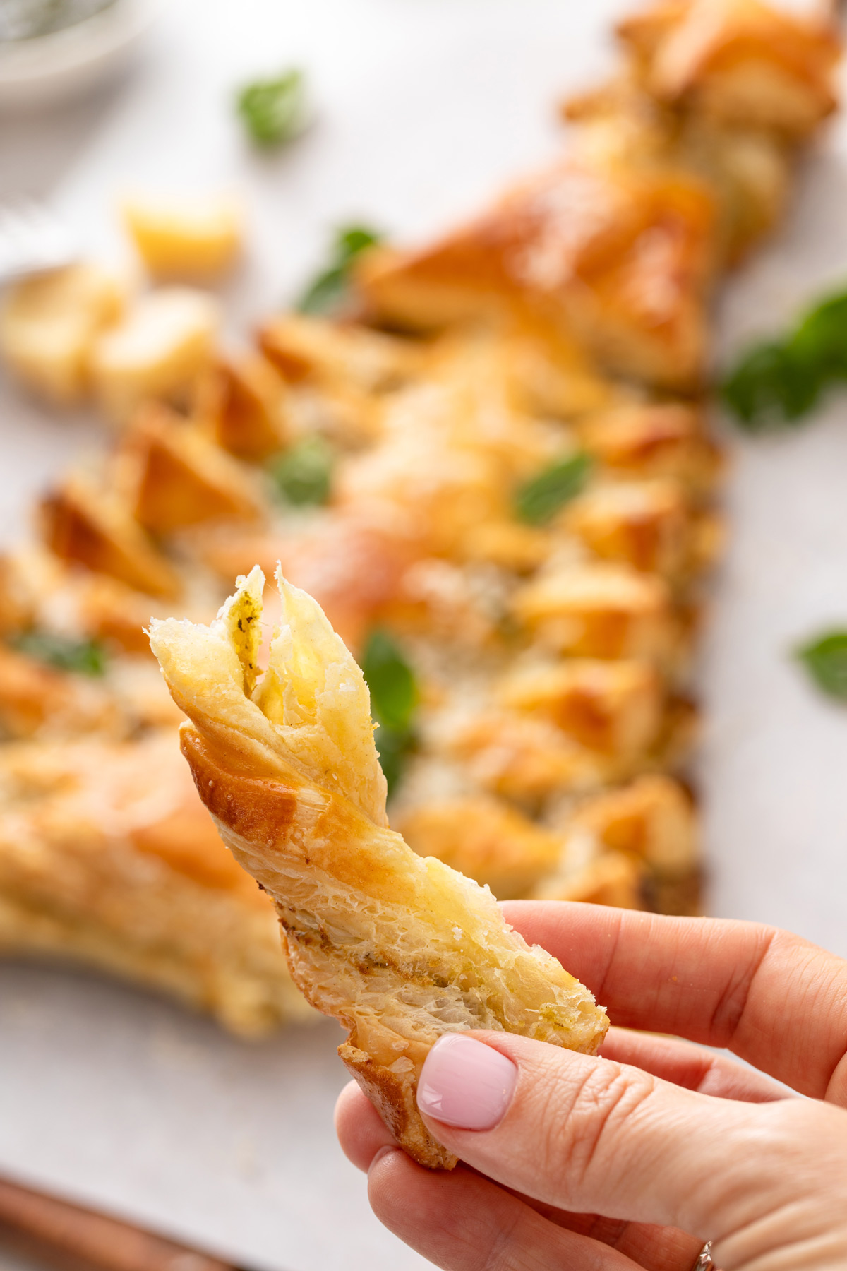 Hand holding up a bite of savory puff pastry christmas tree.