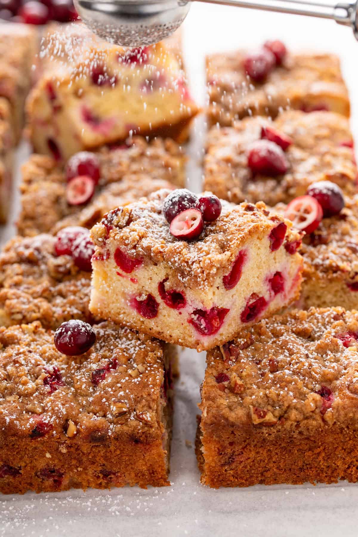 One slice of cranberry cake balanced on top of several other slices of cake.