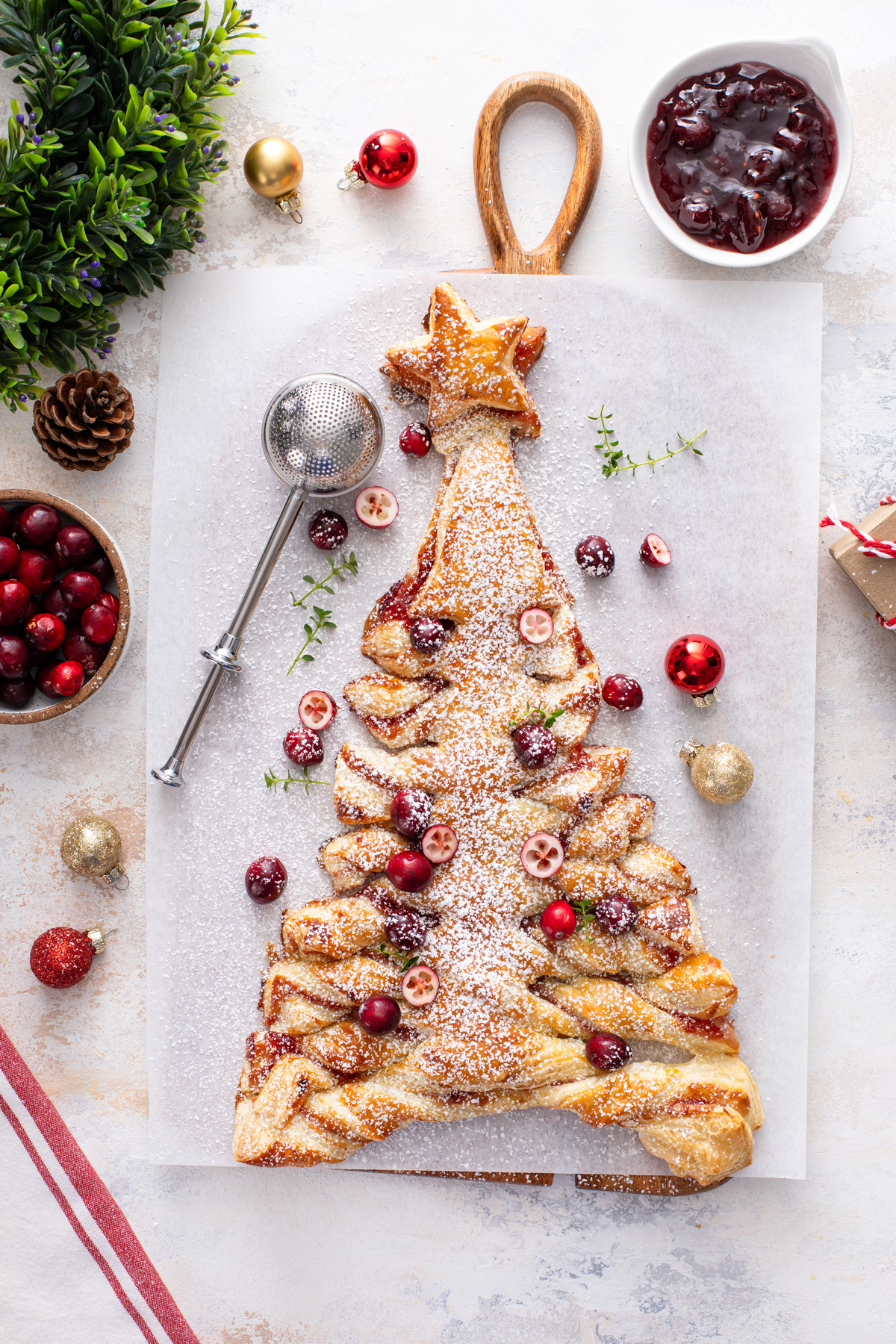 Overhead view of a puff pastry christmas tree filled with cranberry sauce and topped with powdered sugar and cranberries.