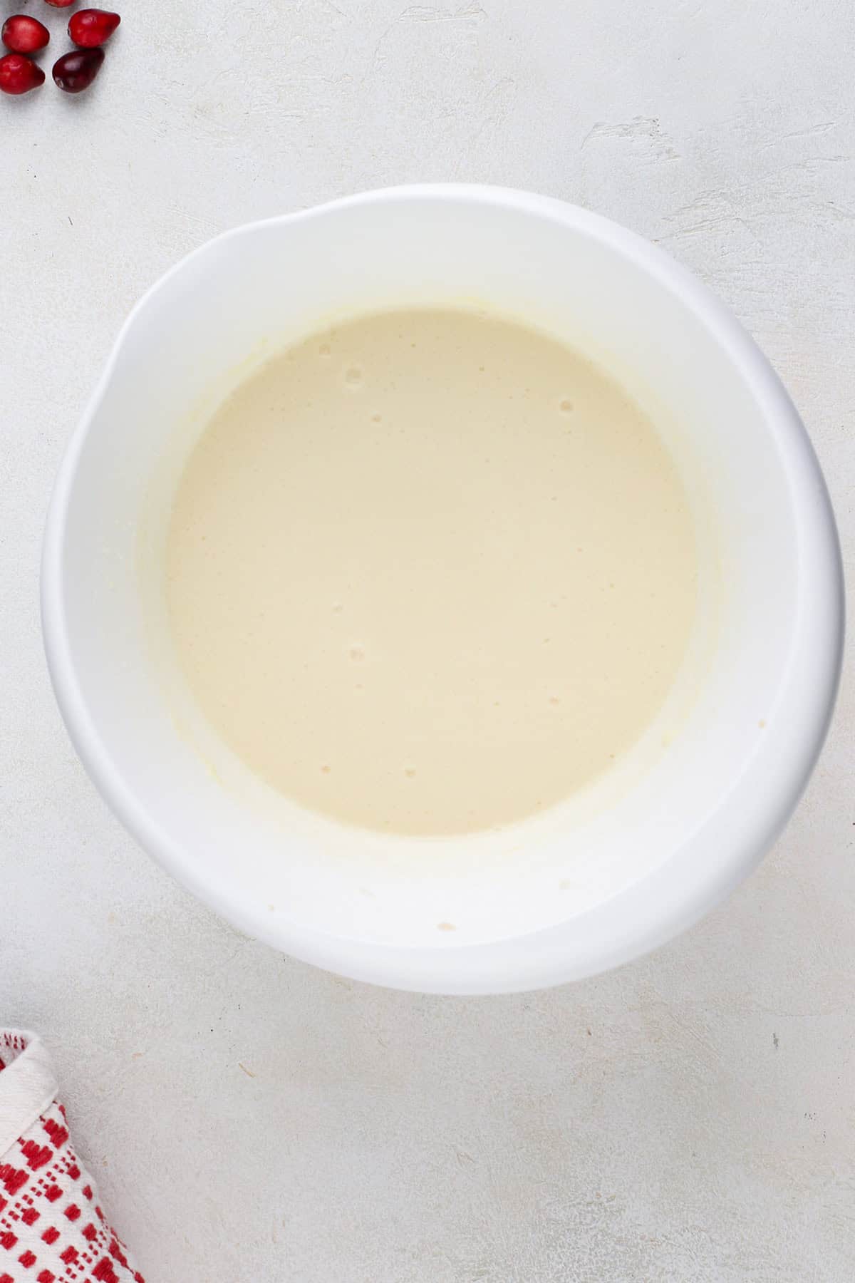 Wet ingredients for cranberry cake mixed in a white bowl.