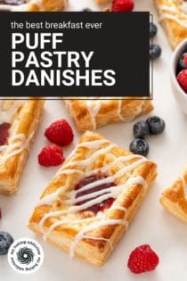 Close up of a puff pastry danish on a white countertop next to mixed berries. Text overlay includes recipe name.