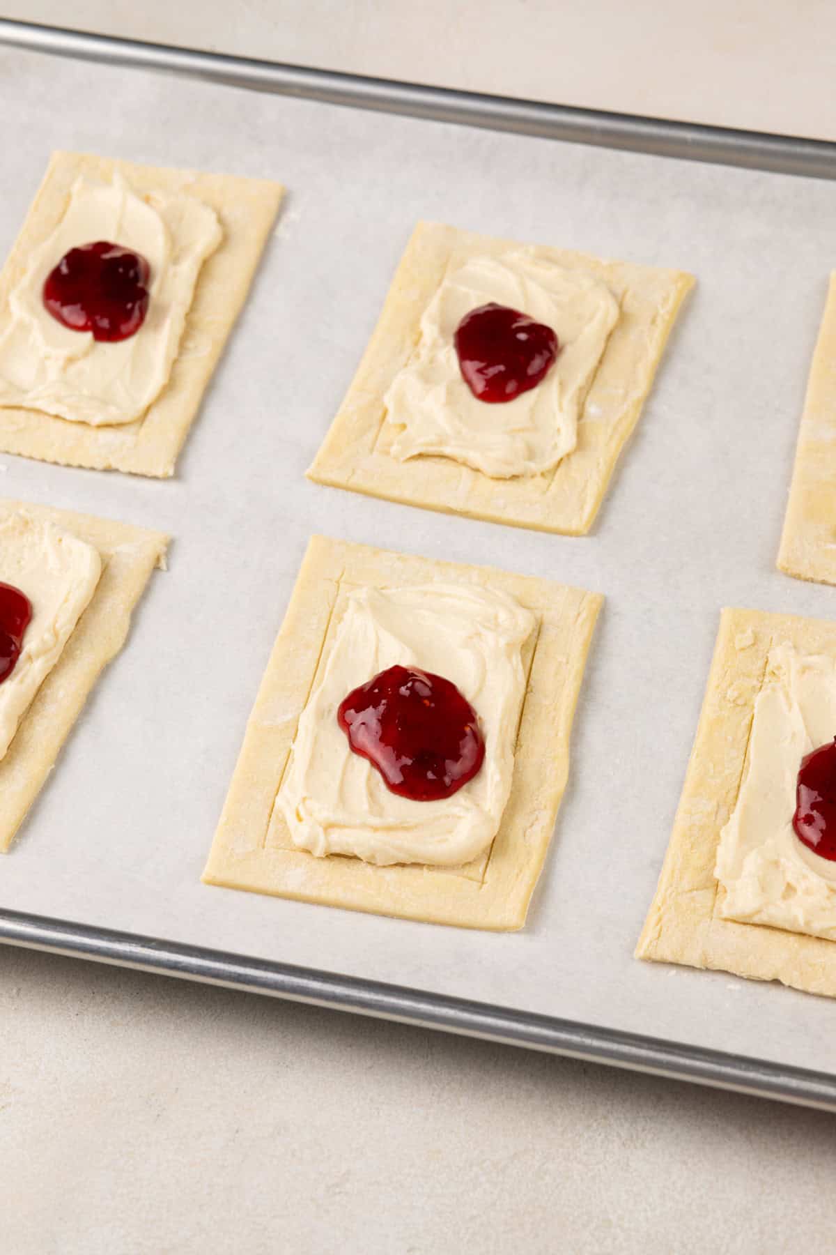 Assembled puff pastry danishes on a parchment-lined baking sheet.