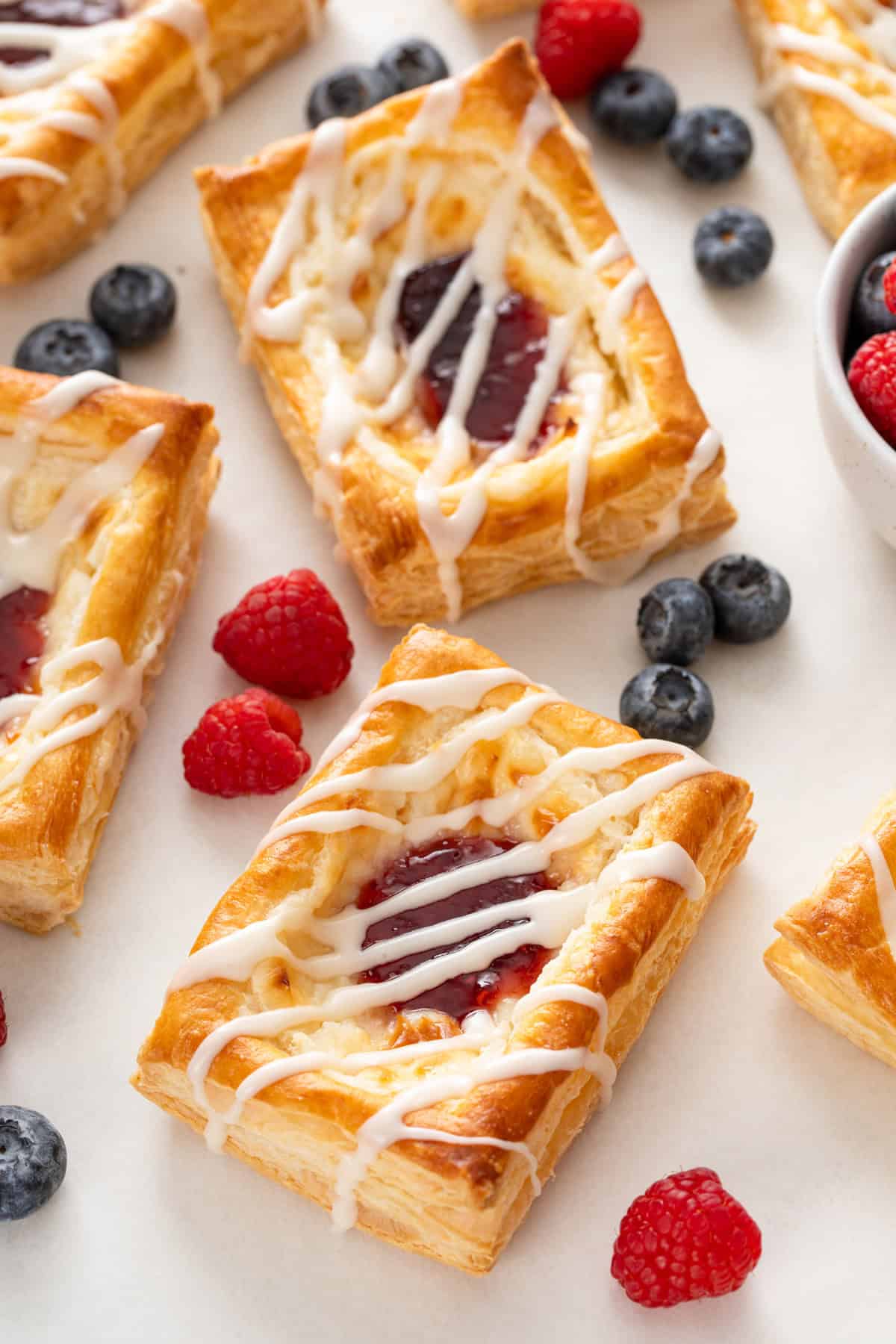 Puff pastry danishes topped with glaze on a white countertop.