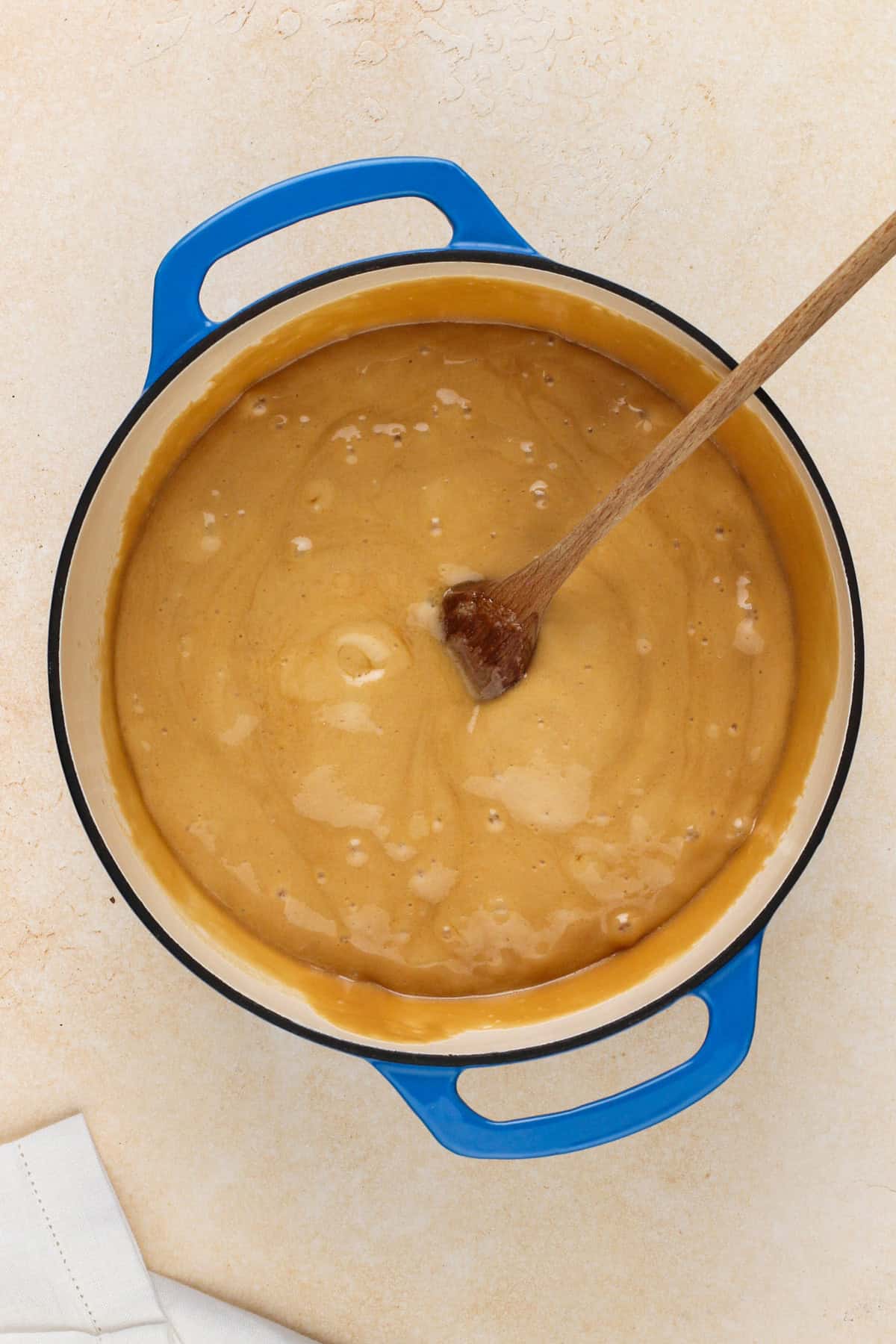 Wooden spoon stirring vanilla and baking soda into caramel sauce.