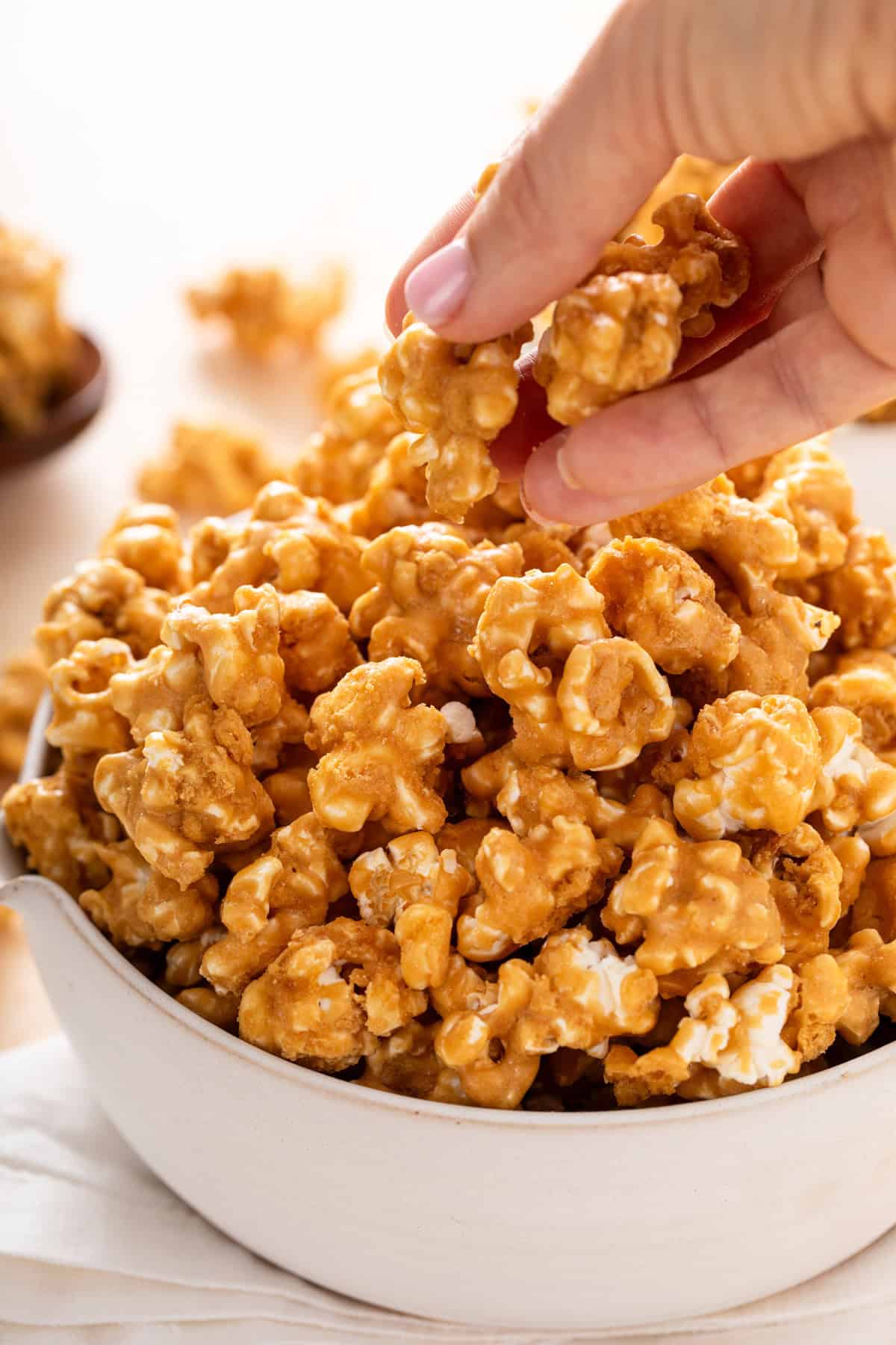 Hand picking up several pieces of caramel corn from a bowl.