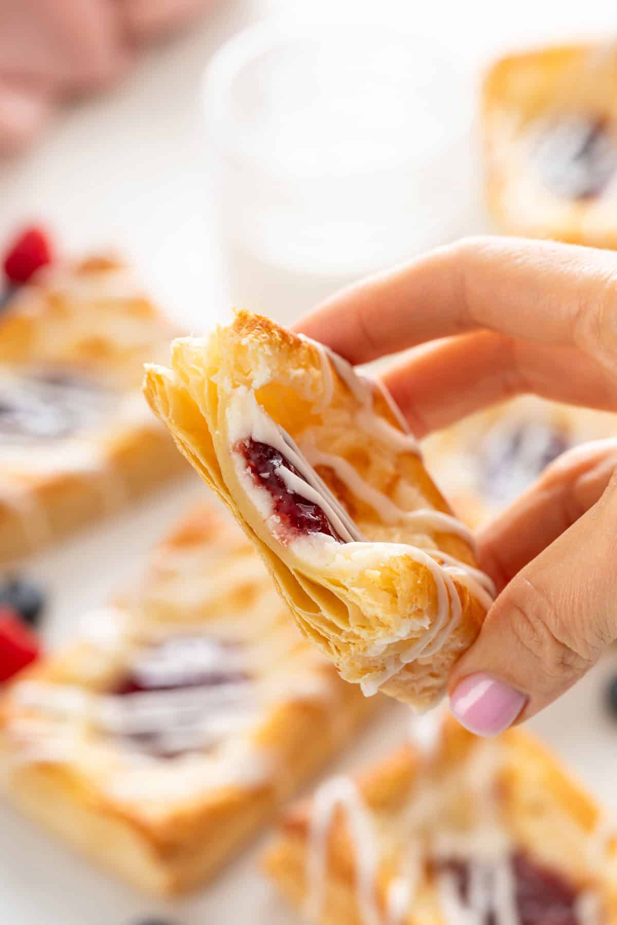 Hand holding up a halved puff pastry danish.