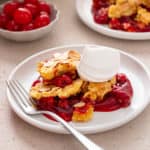 Cherry dump cake next to a fork on a plate.