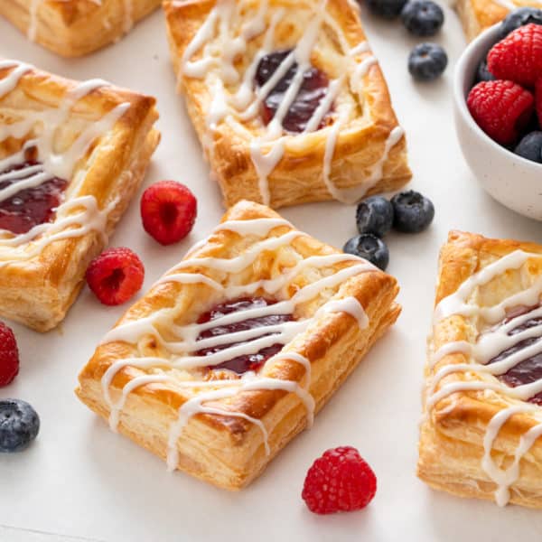 Several puff pastry danishes on a countertop with fresh berries.