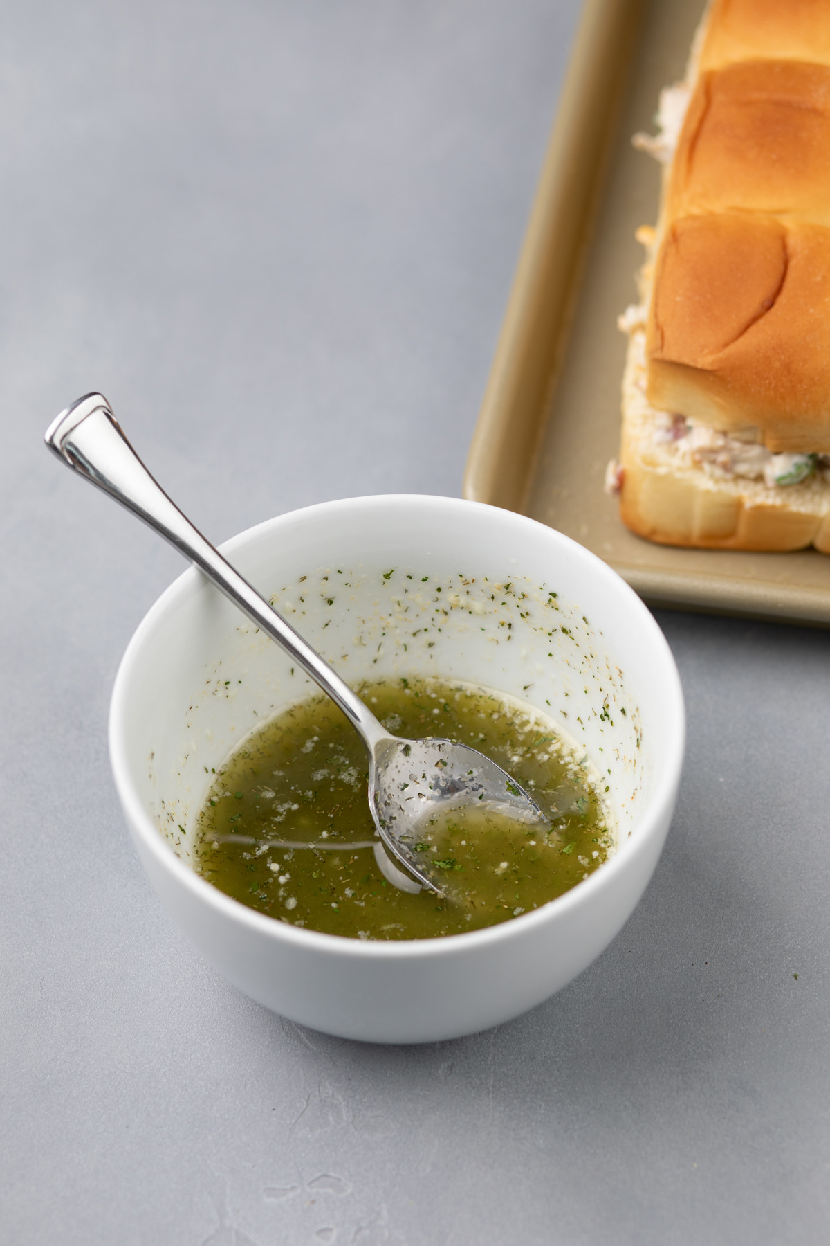 Seasoned garlic butter for sliders in a white bowl.