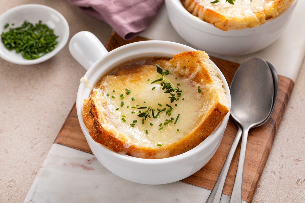 French onion soup topped with cheese toast in a white bowl.