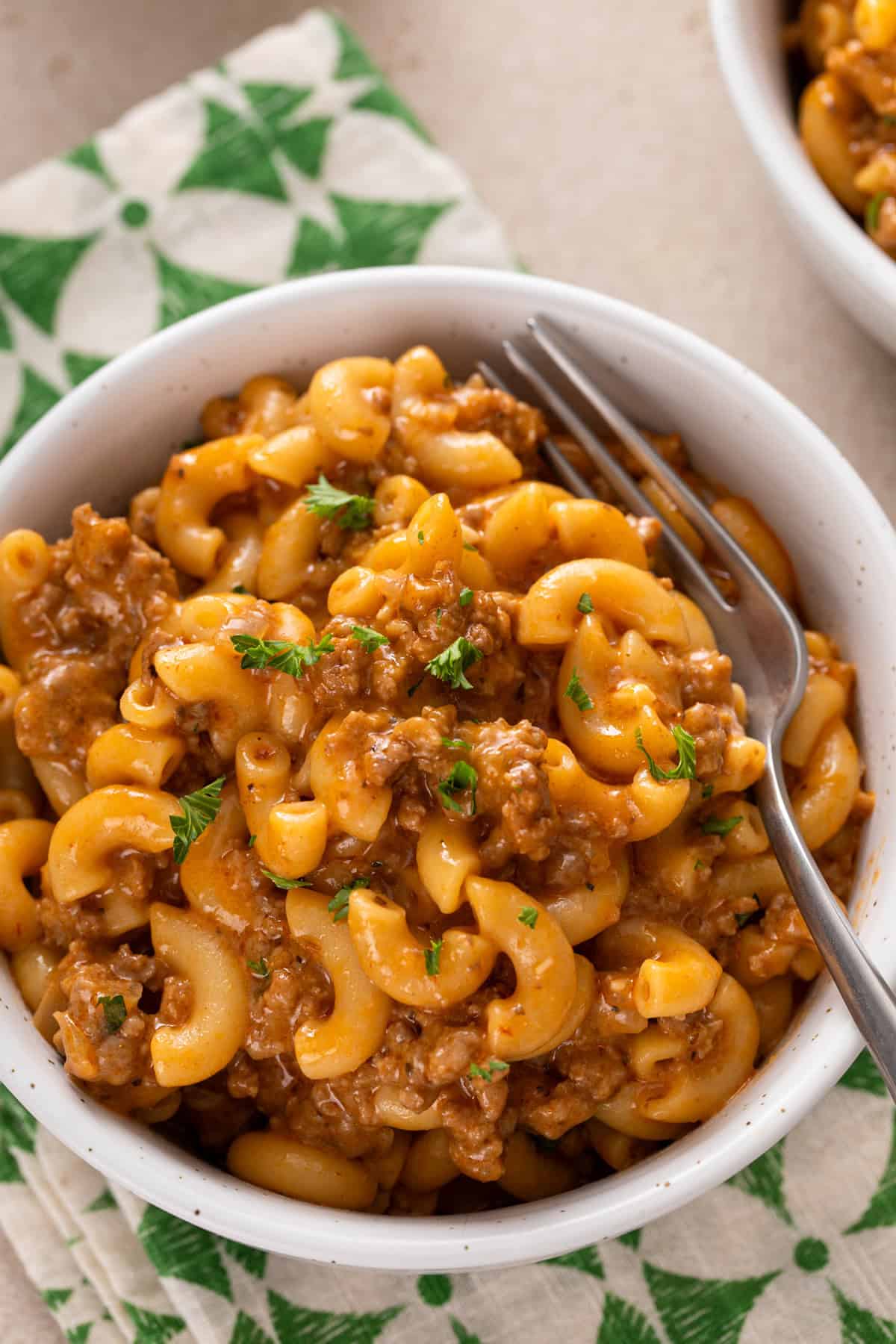 Close up view of a fork in a bowl of homemade cheeseburger helper.