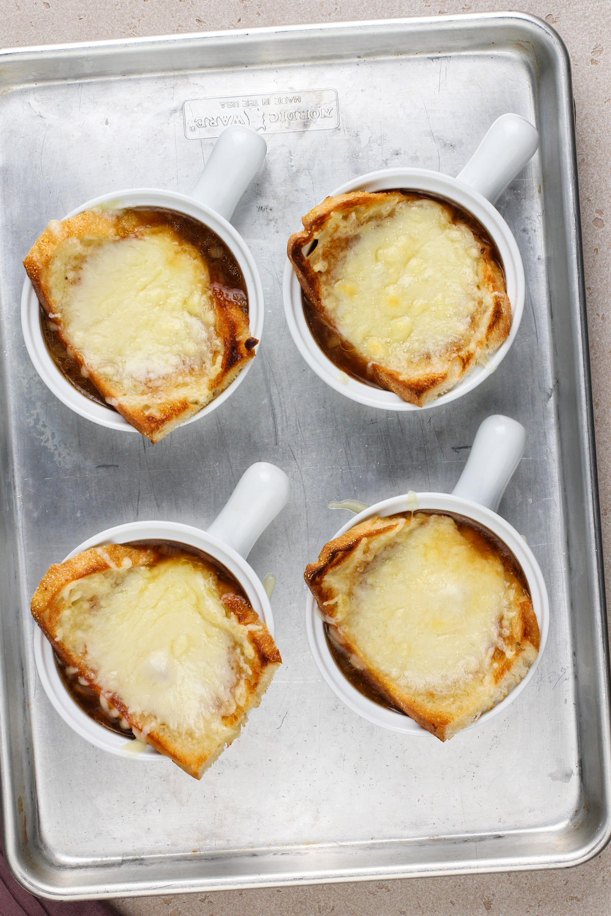 Four bowls of french onion soup freshly pulled from under the broiler.