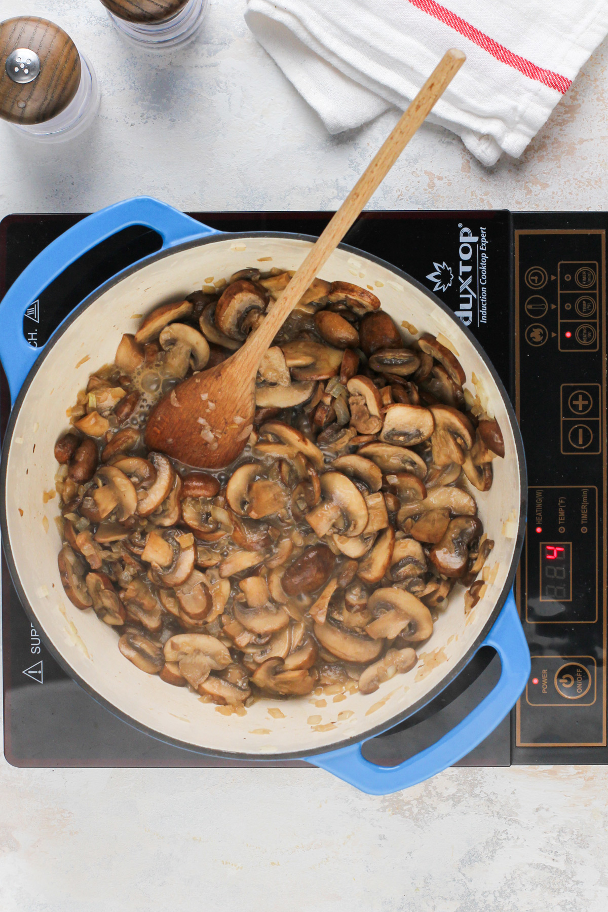 Cooked mushrooms and onions in a blue dutch oven.