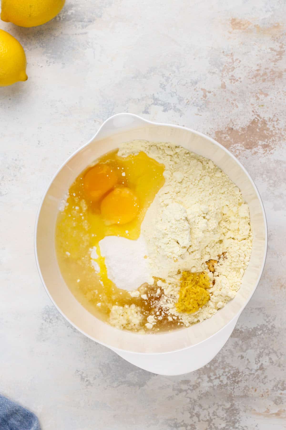 Ingredients for lemon crinkle cookies in a white mixing bowl.