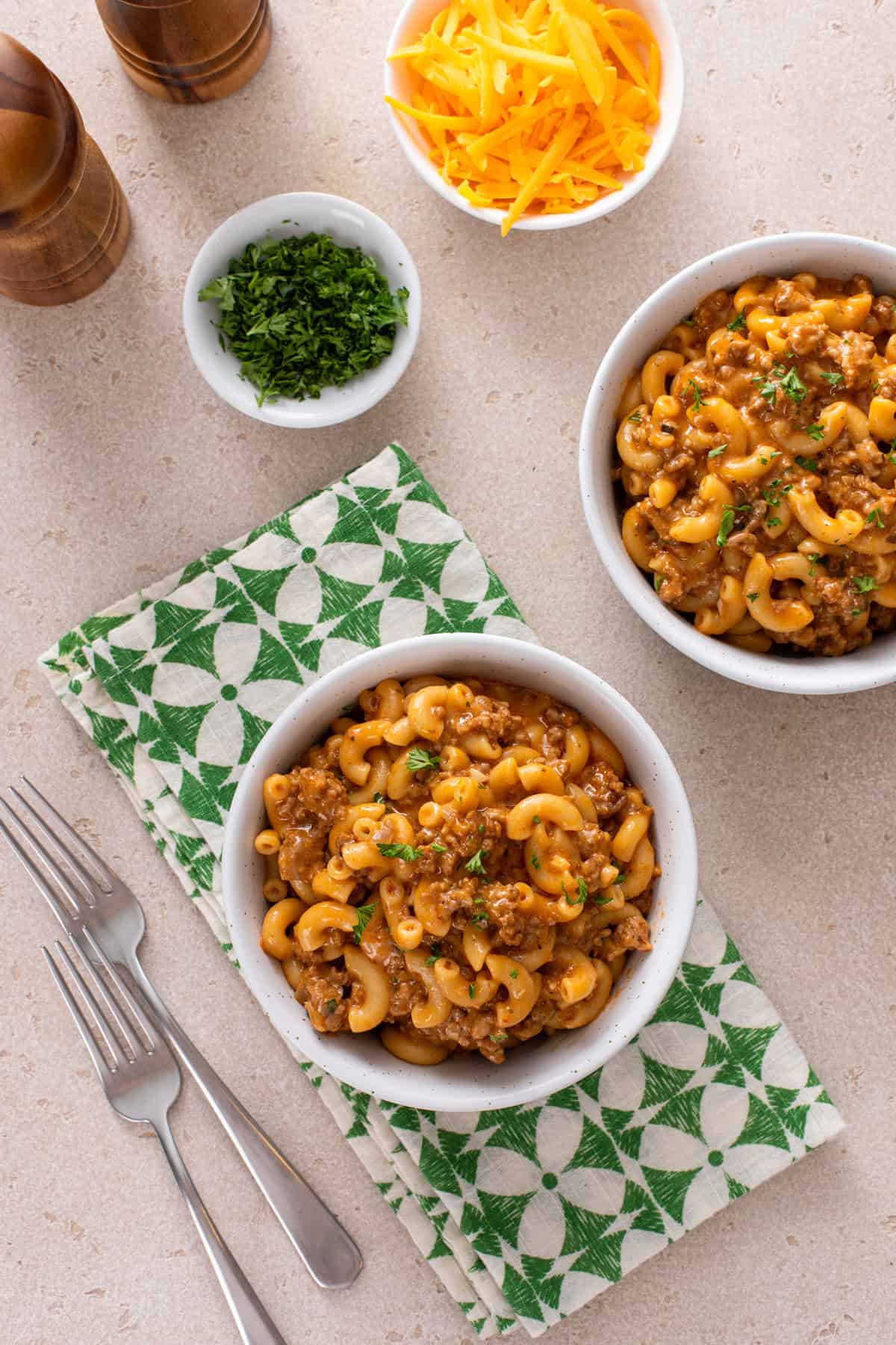 Overhead view of two white bowls filled with homemade cheeseburger helper on a countertop.