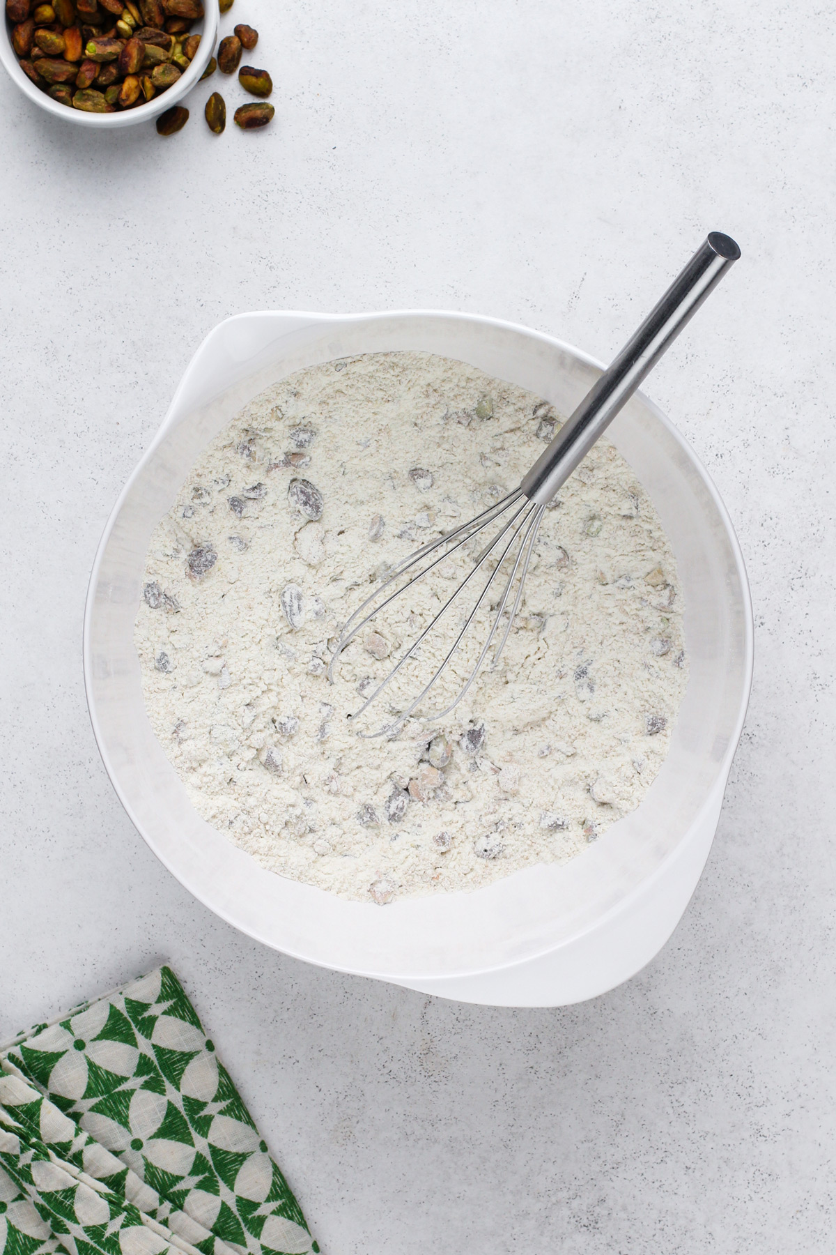 Dry ingredients for pistachio muffins whisked in a white bowl.