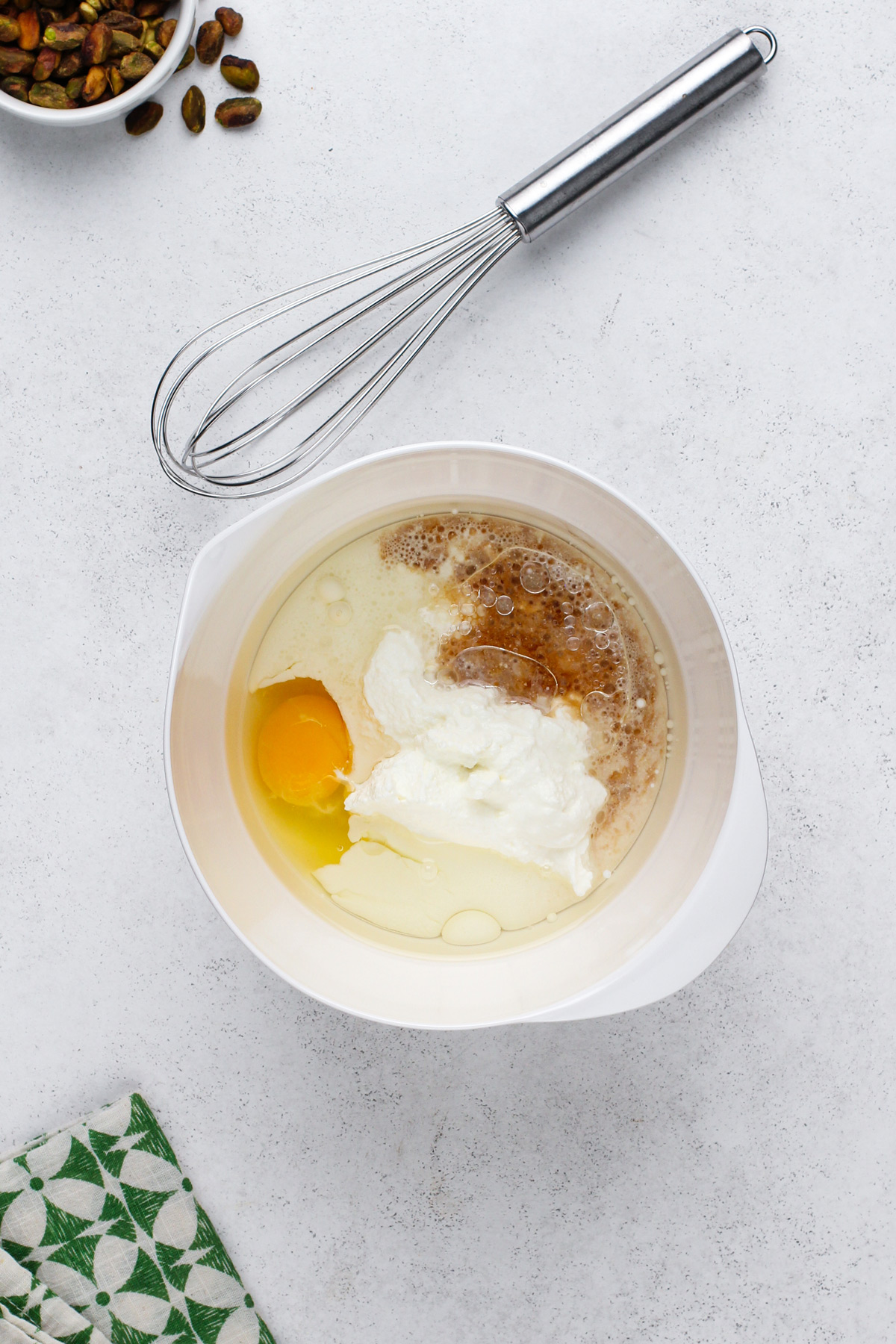 Wet ingredients for pistachio muffins in a white bowl.