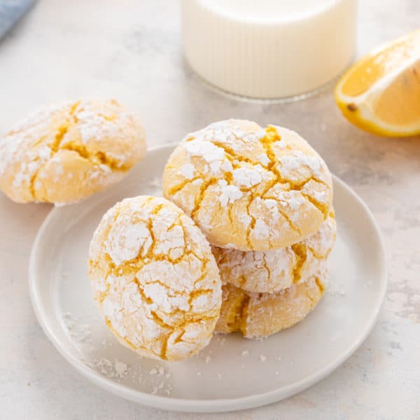 Four lemon crinkle cookies on a white plate.