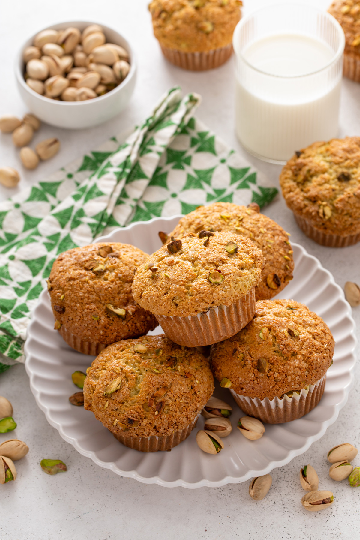 Five pistachio muffins arranged on a white plate.