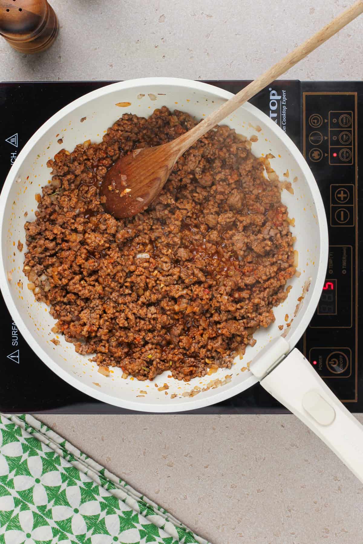 Cooked ground beef and onions in a skillet with tomato paste.