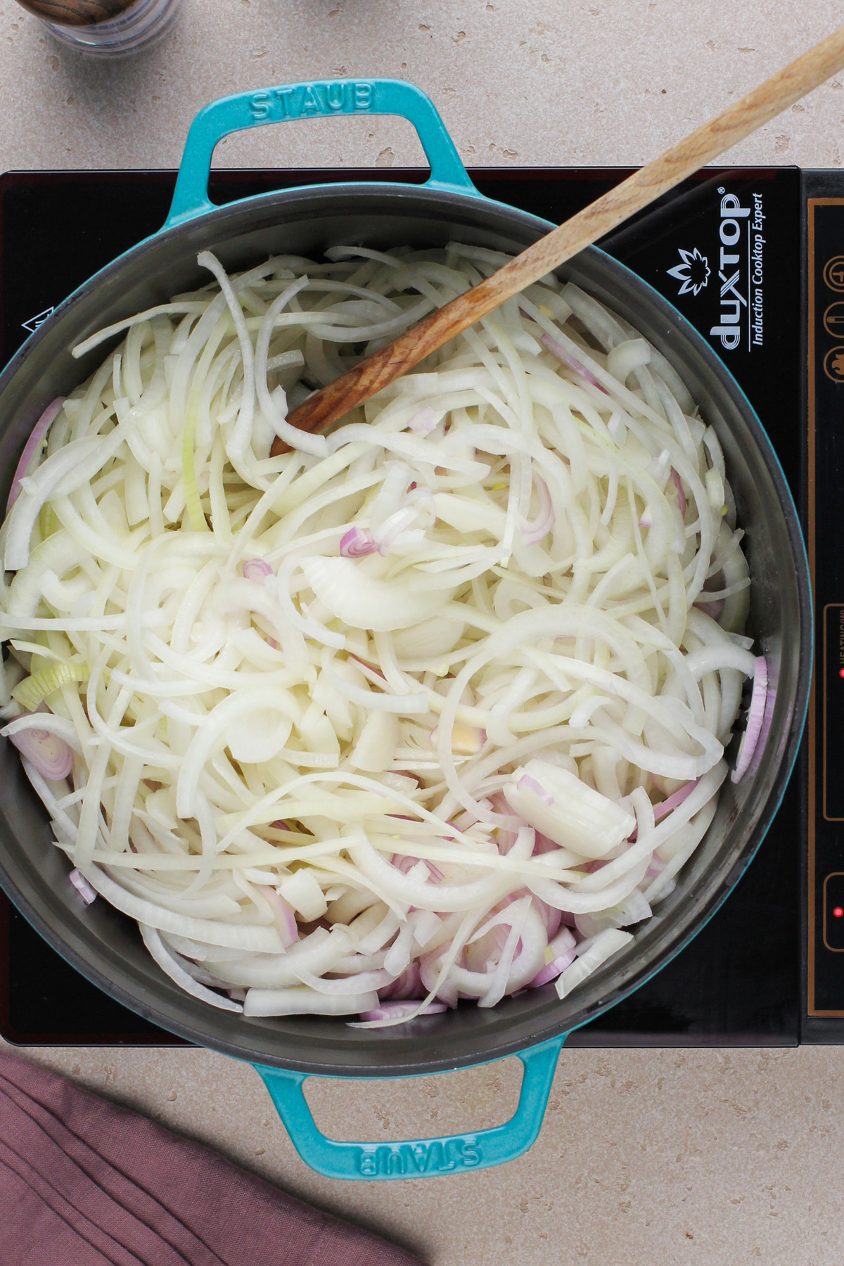 Sliced onions and shallots in a soup pot.