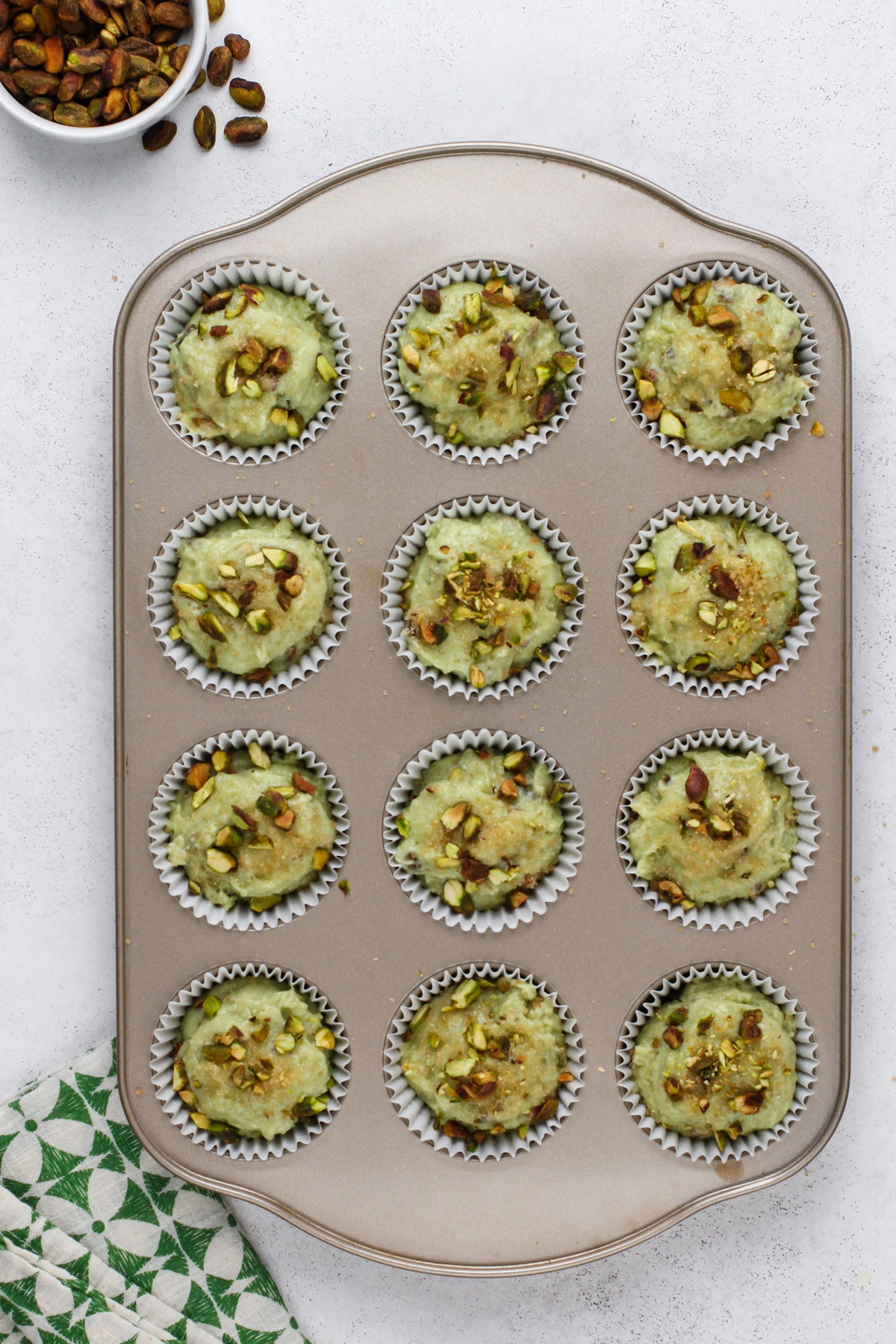 Unbaked pistachio muffins in a muffin tin, ready to go in the oven.