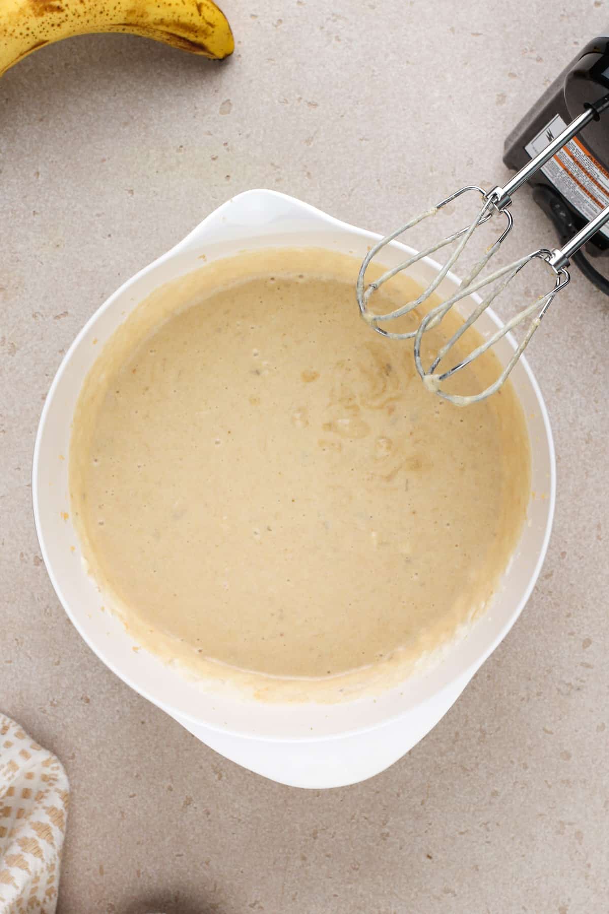 Wet ingredients for sour cream banana bread mixed in a white bowl.