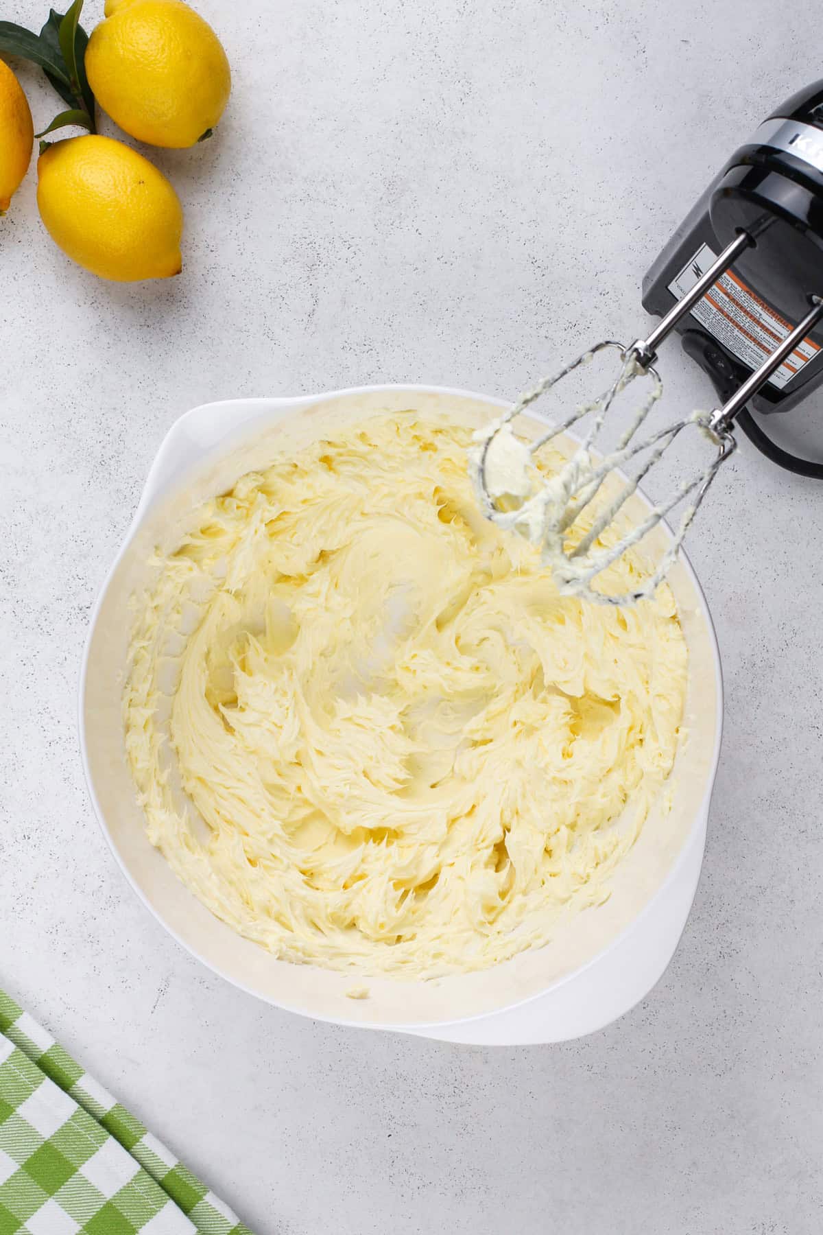 Butter being beaten with an electric mixer in a white bowl.