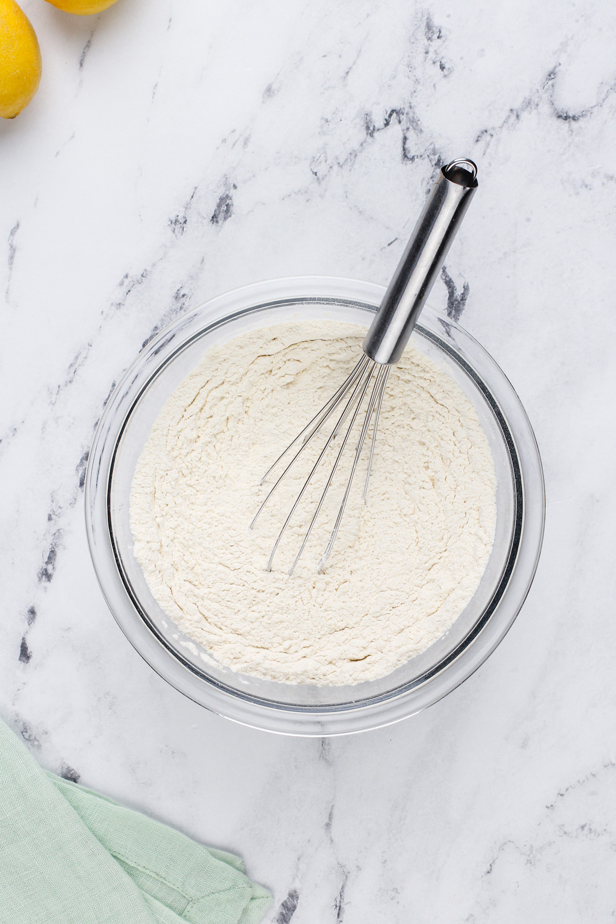 Dry ingredients for lemon cookies whisked in a glass bowl.