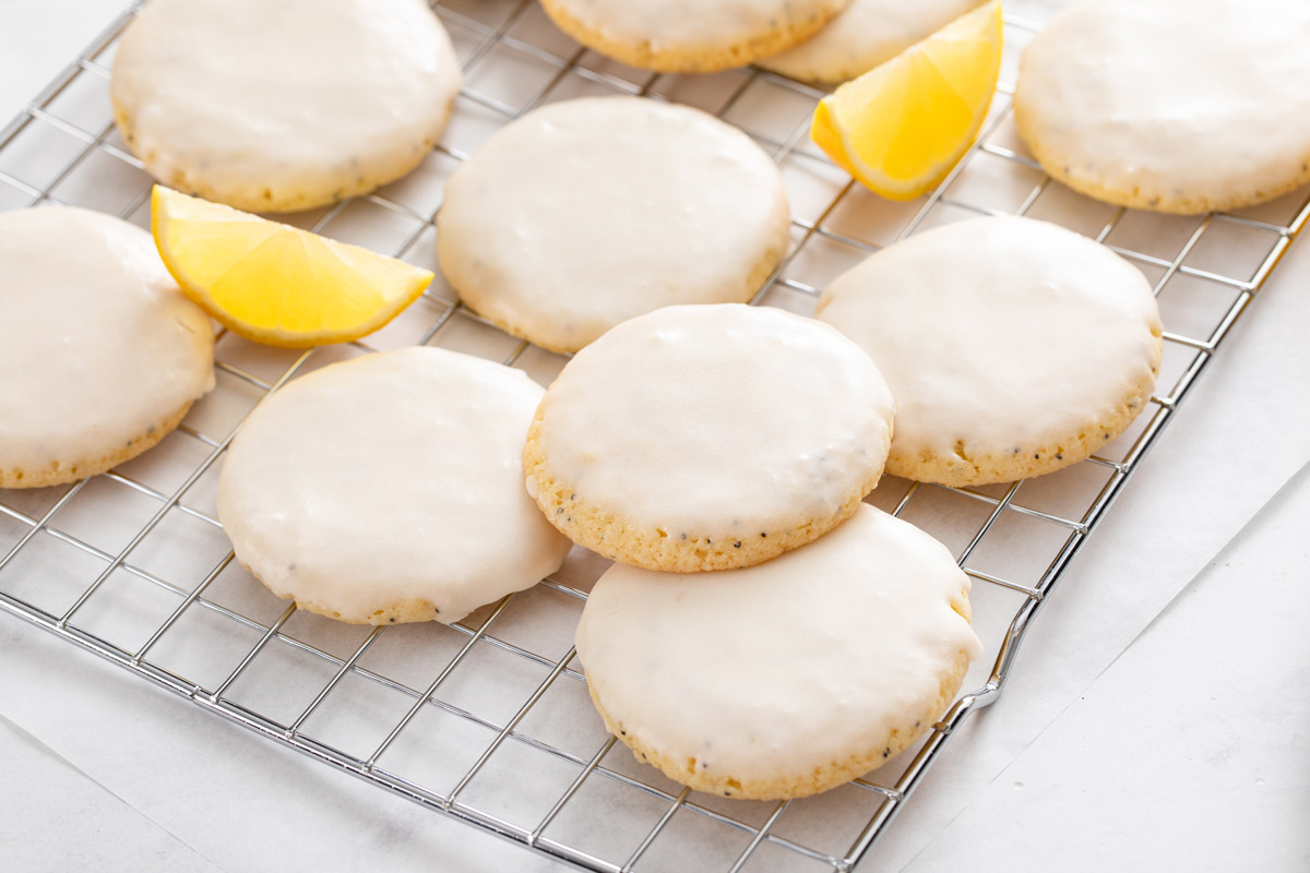 Glazed lemon poppy seed cookies arranged on a wire rack.