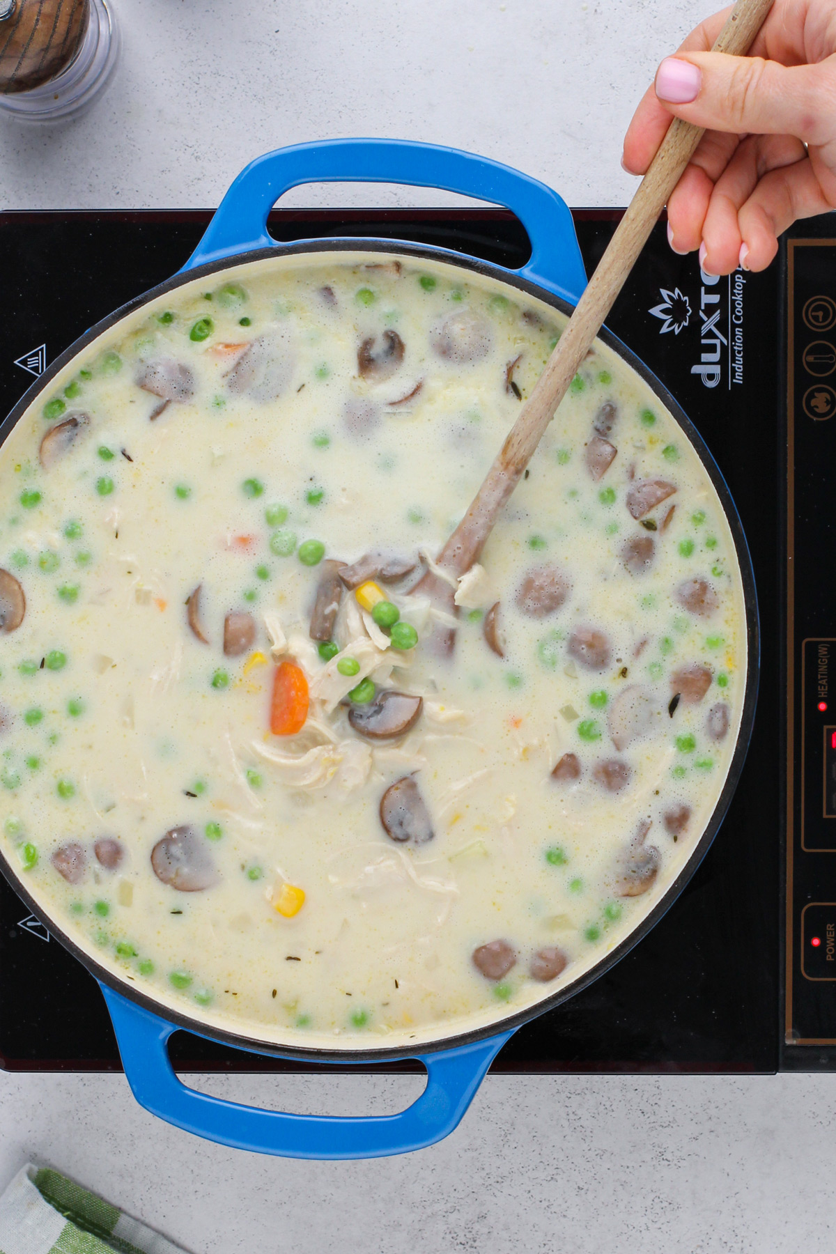 Stirring cream into chicken pot pie soup.