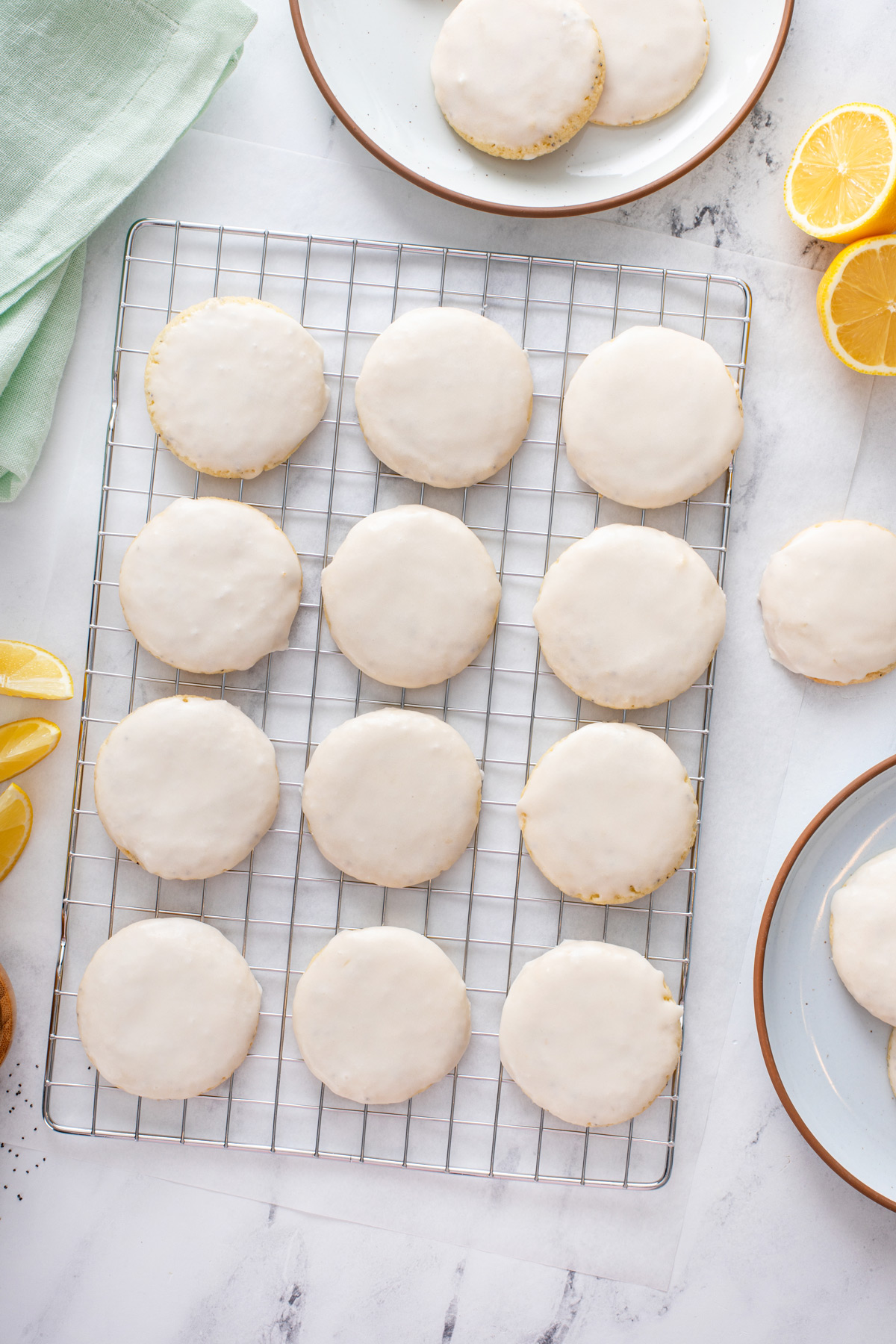 Overhead view of glazed lemon poppy seed cookies lined up on a wire rack.