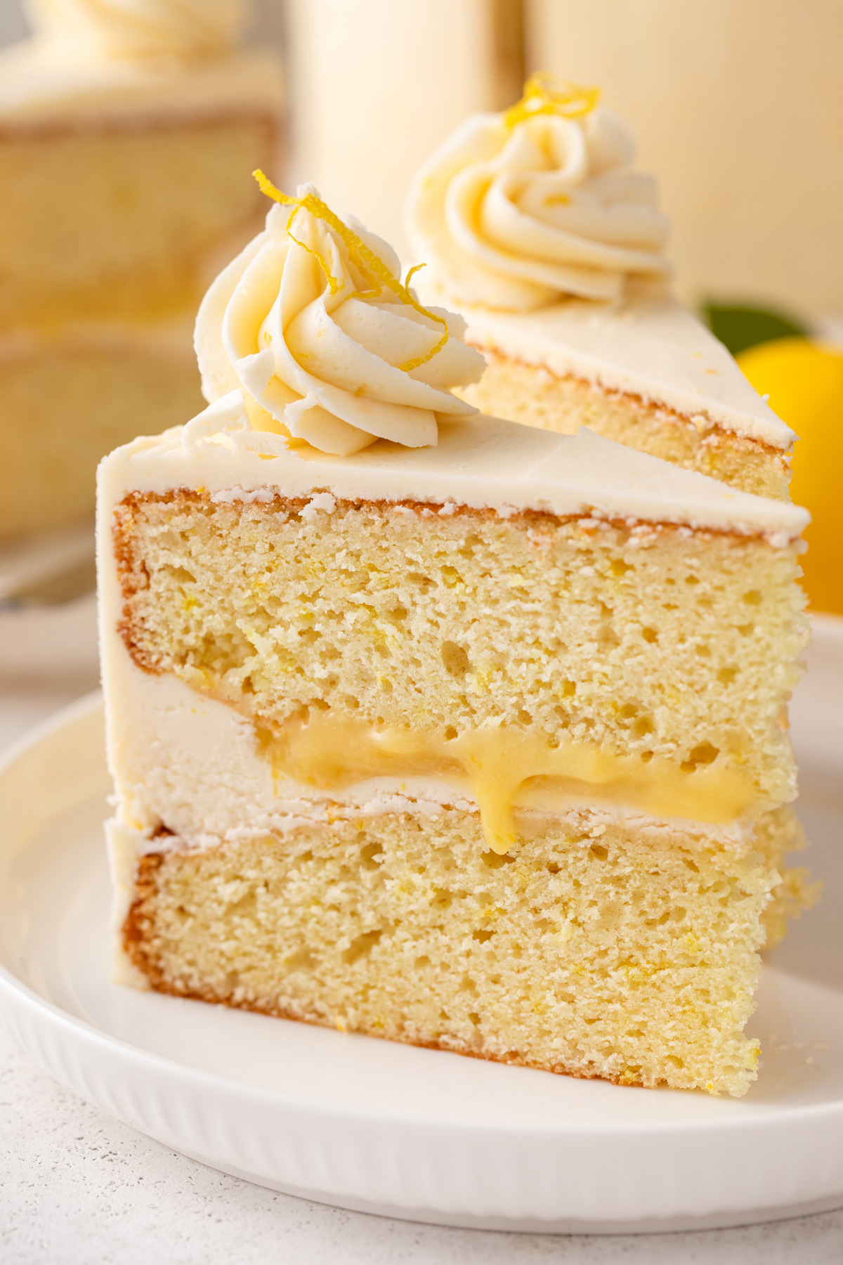 Close up of a slice of lemon layer cake on a white plate.