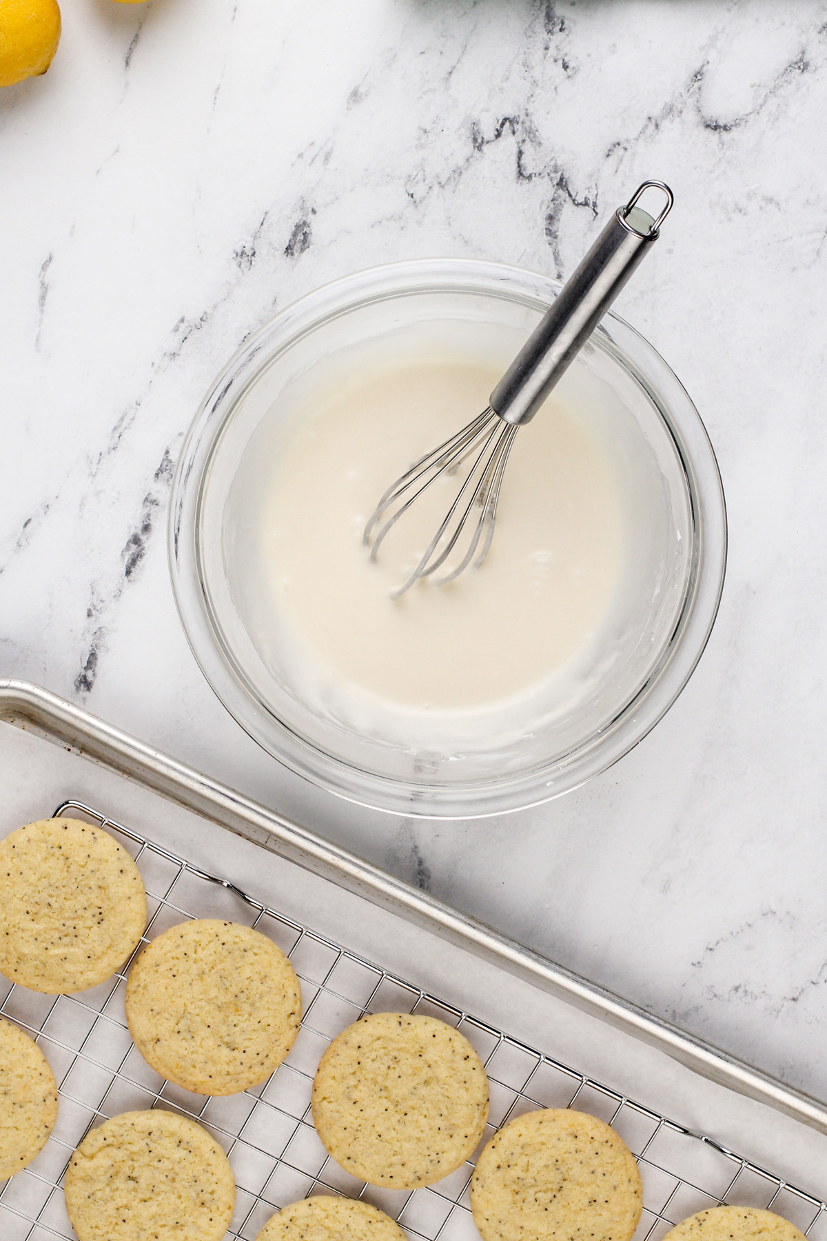 Bowl of lemon glaze next to cooled lemon poppy seed cookies.