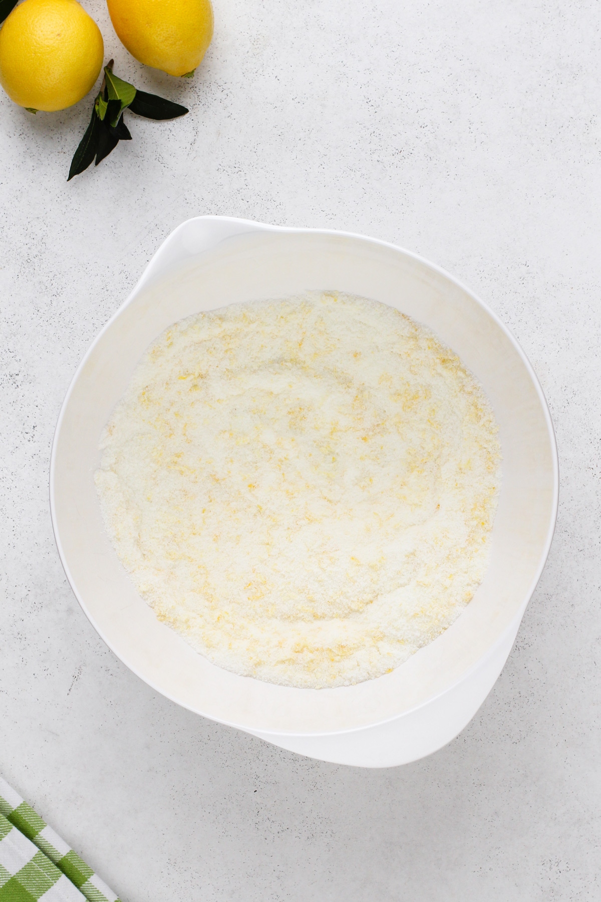 Granulated sugar and lemon zest mixed in a white bowl.