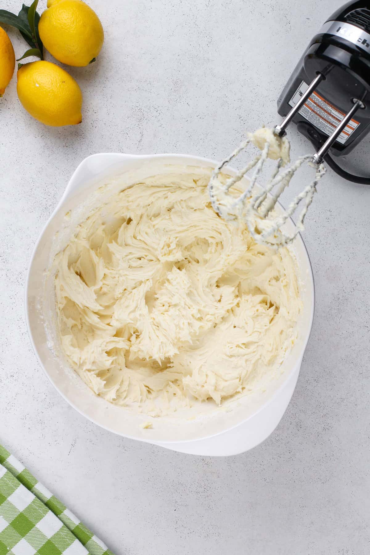 Ingredients for lemon buttercream being mixed in a white bowl.