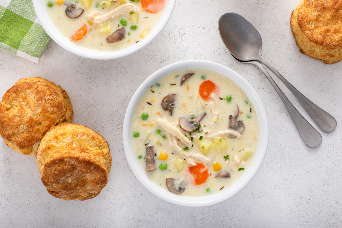 Overhead view of two white bowls on a countertop, each holding chicken pot pie soup.