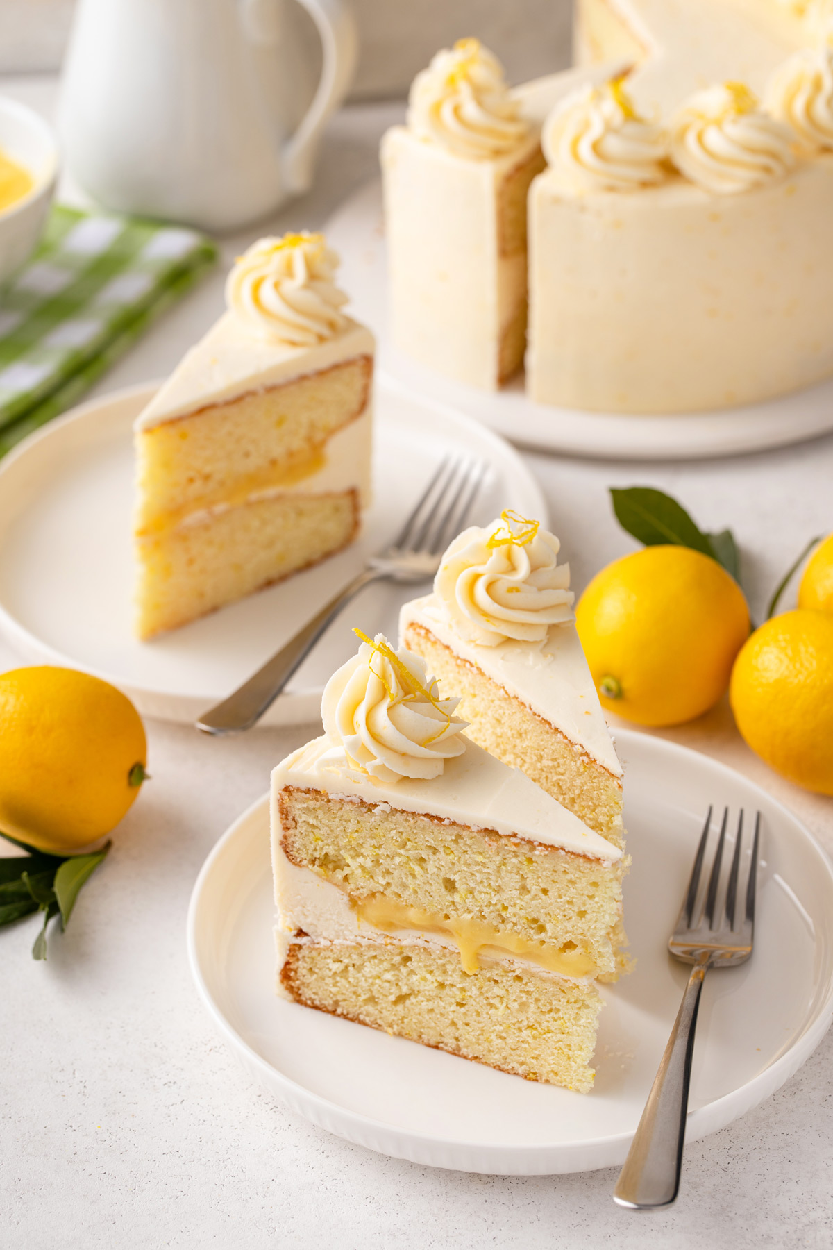 Two white plates, each holding slices of lemon layer cake and forks.