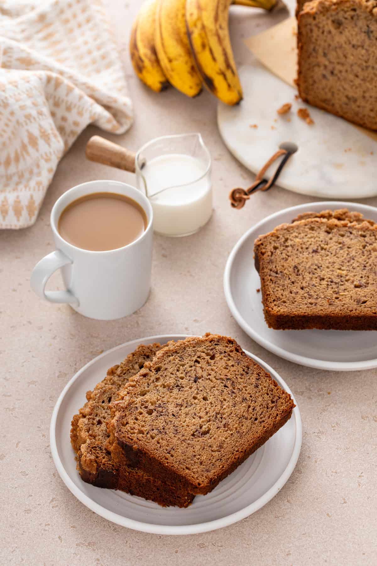 Two white plates, each holding two slices of sour cream banana bread.