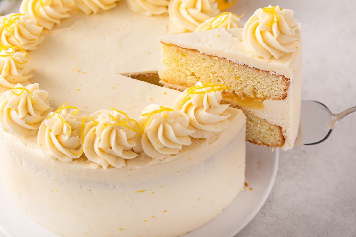 Cake server lifting up a slice of lemon layer cake.