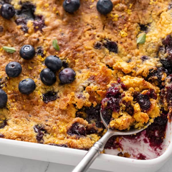 Serving spoon in a pan of blueberry dump cake.