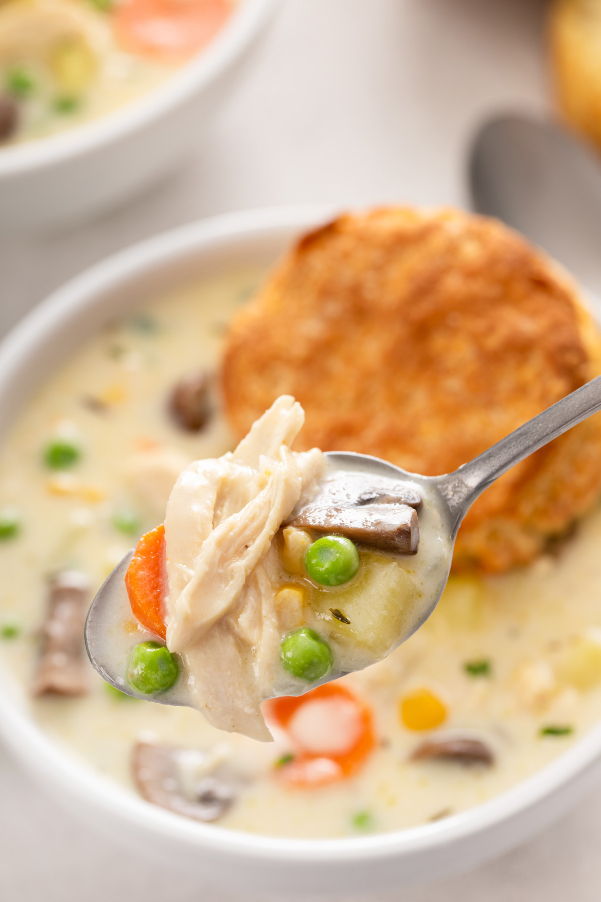 Spoon holding up a bite of chicken pot pie soup.