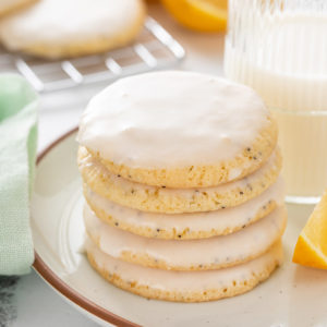 Stack of lemon poppy seed cookies in front of a glass of milk.